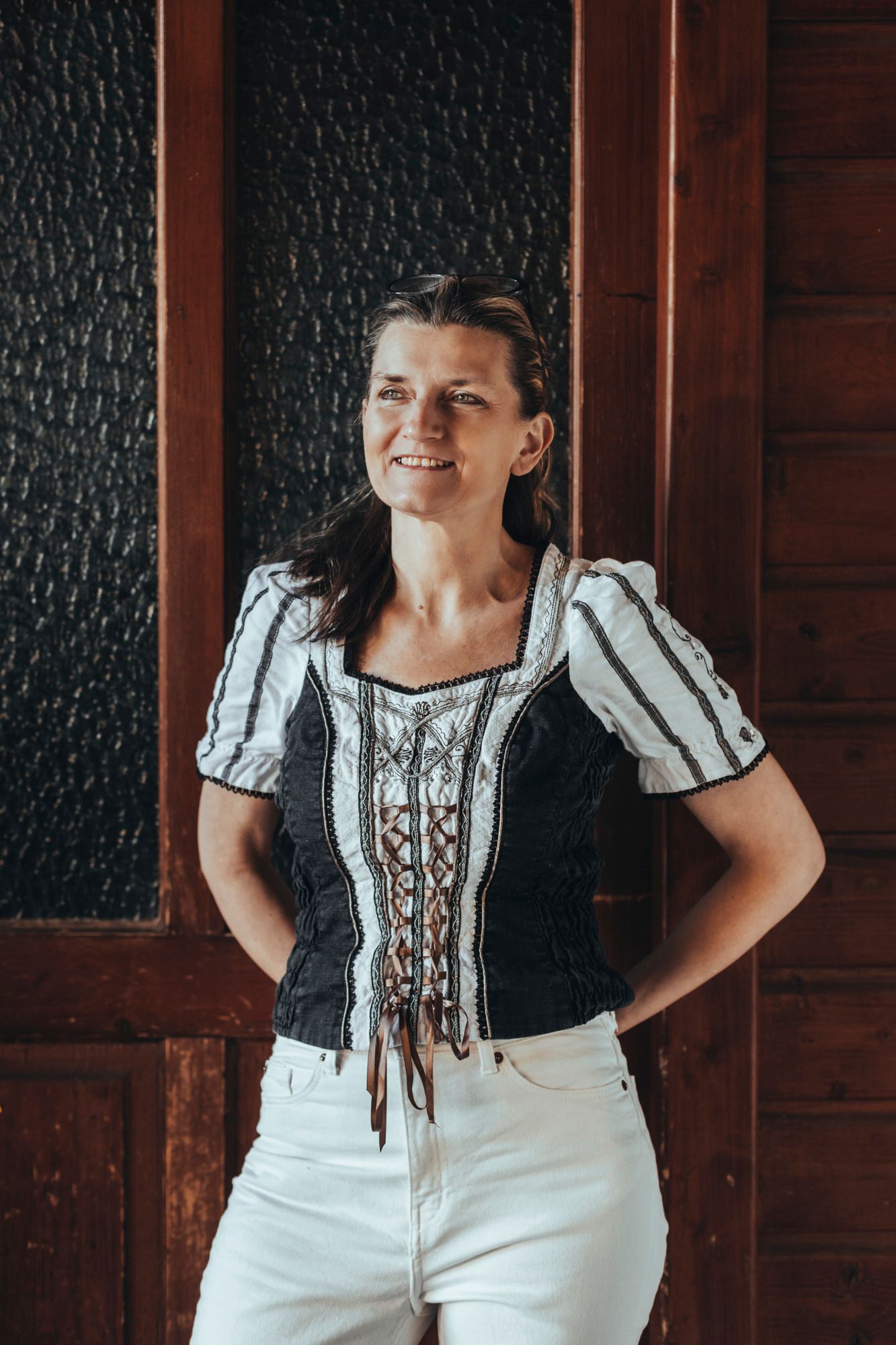 Frau in traditioneller Kleidung vor Holzwand.