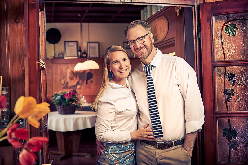 Elegantes Restaurant mit gedeckten Tischen, modernen Lampen und Blumenarrangement.