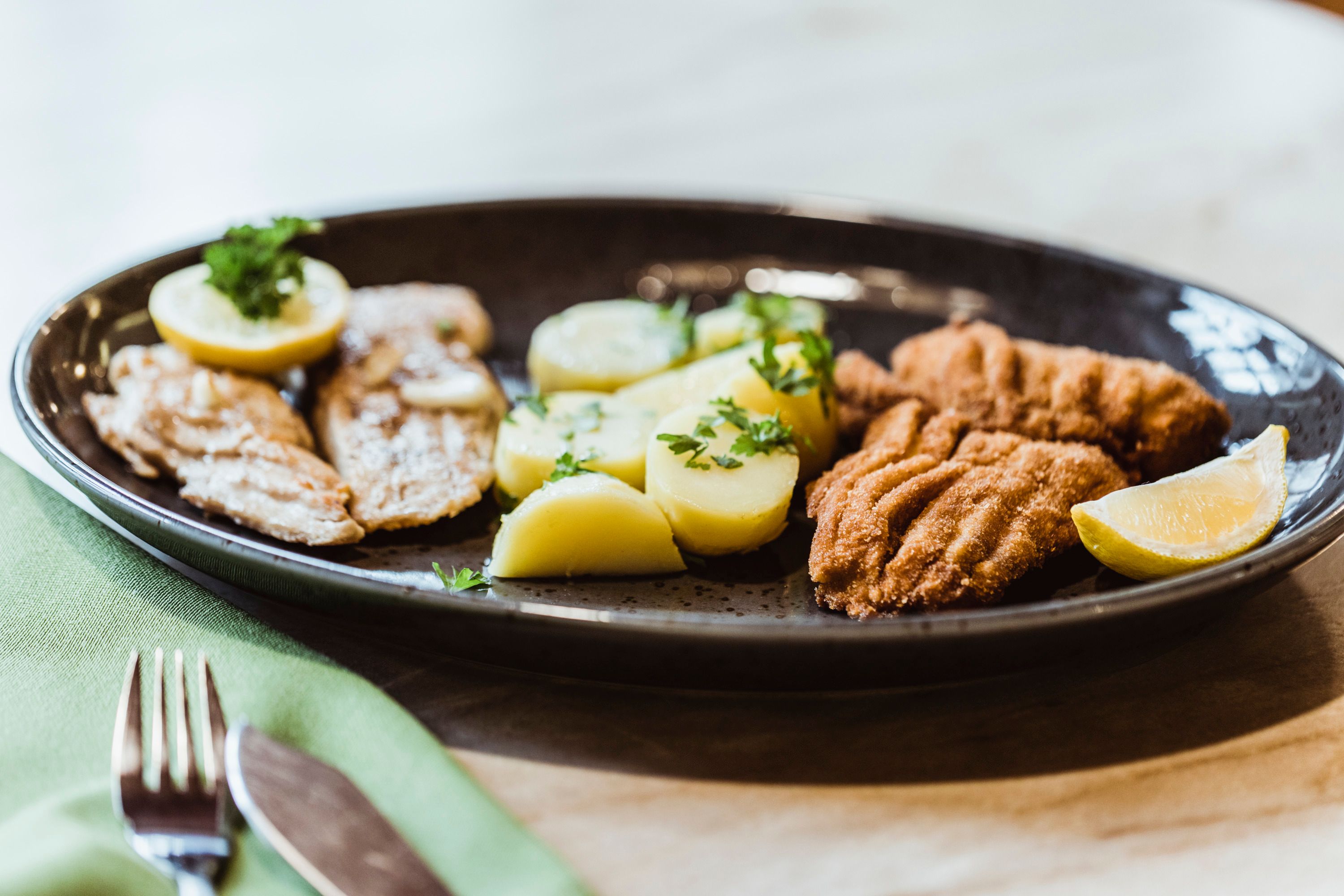 Ein Teller mit Fisch, Kartoffeln und Zitronenscheiben.