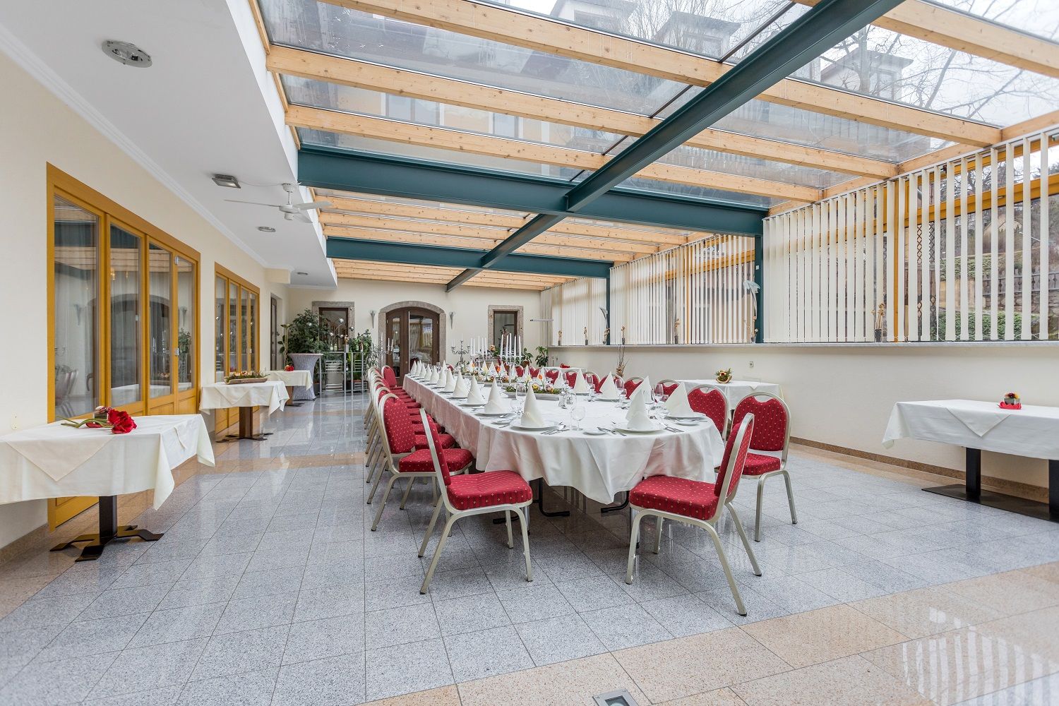 Eleganter Wintergarten mit gedecktem Tisch und roten Stühlen.