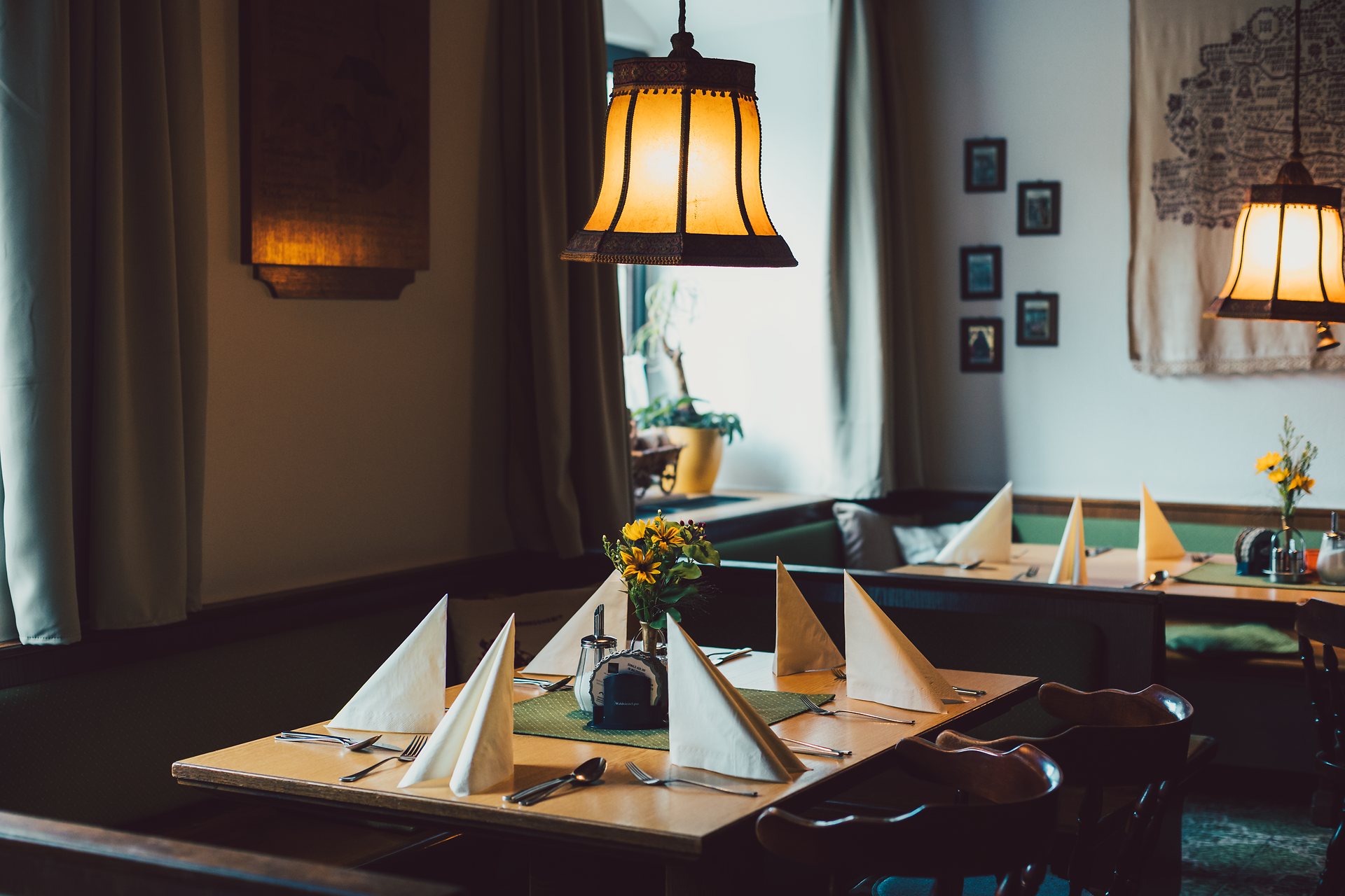 Die gemütliche Gaststube des Nordwaldhofs lädt mit warmem Licht und liebevoll gedeckten Tischen zum Verweilen ein. Hier genießen Gäste die herzliche Wirtshauskultur und die kulinarischen Köstlichkeiten der Region. Frische Blumen auf den Tischen verleihen dem Raum eine einladende Atmosphäre.