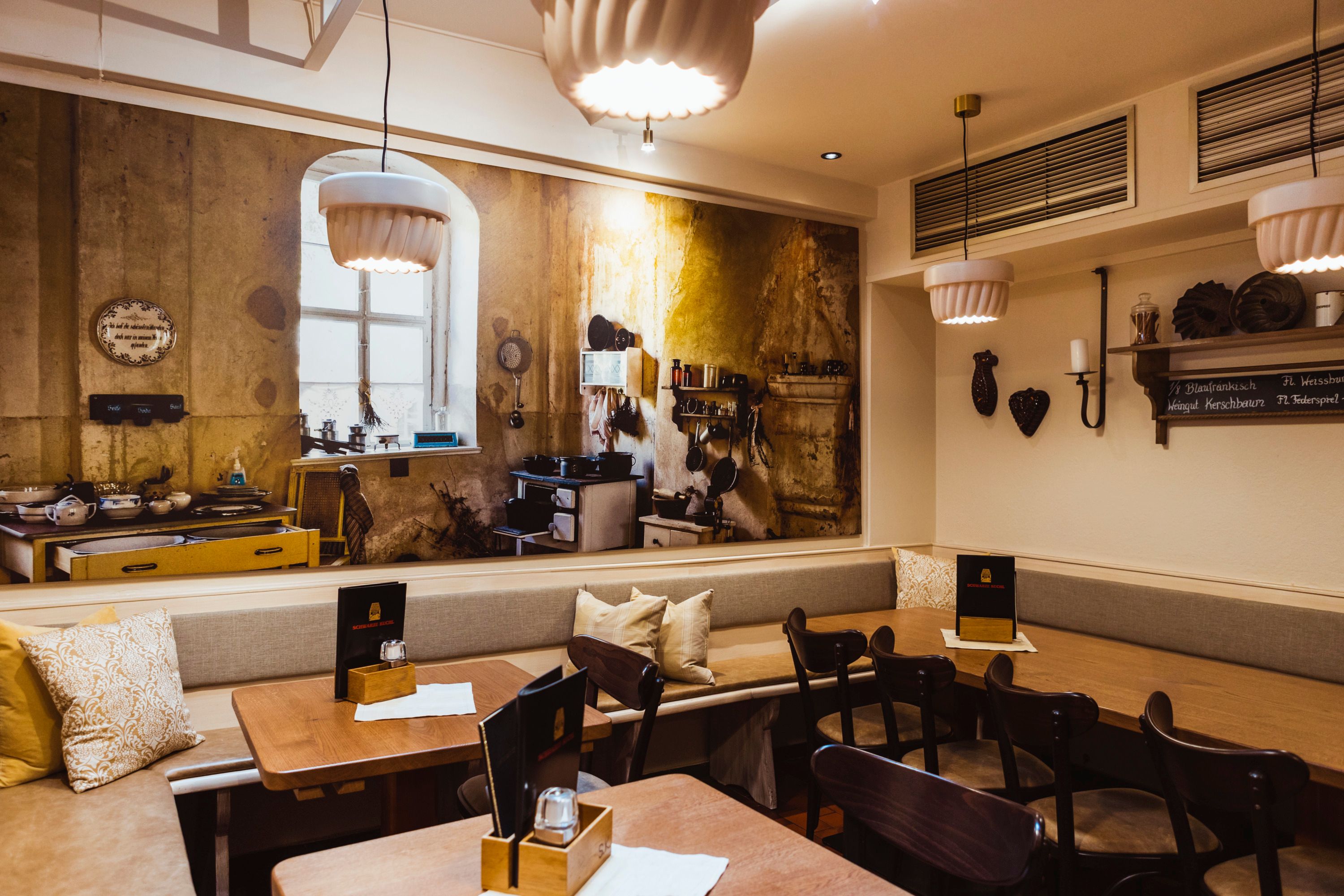 Gemütliches Restaurant mit rustikalem Wandbild einer alten Küche.