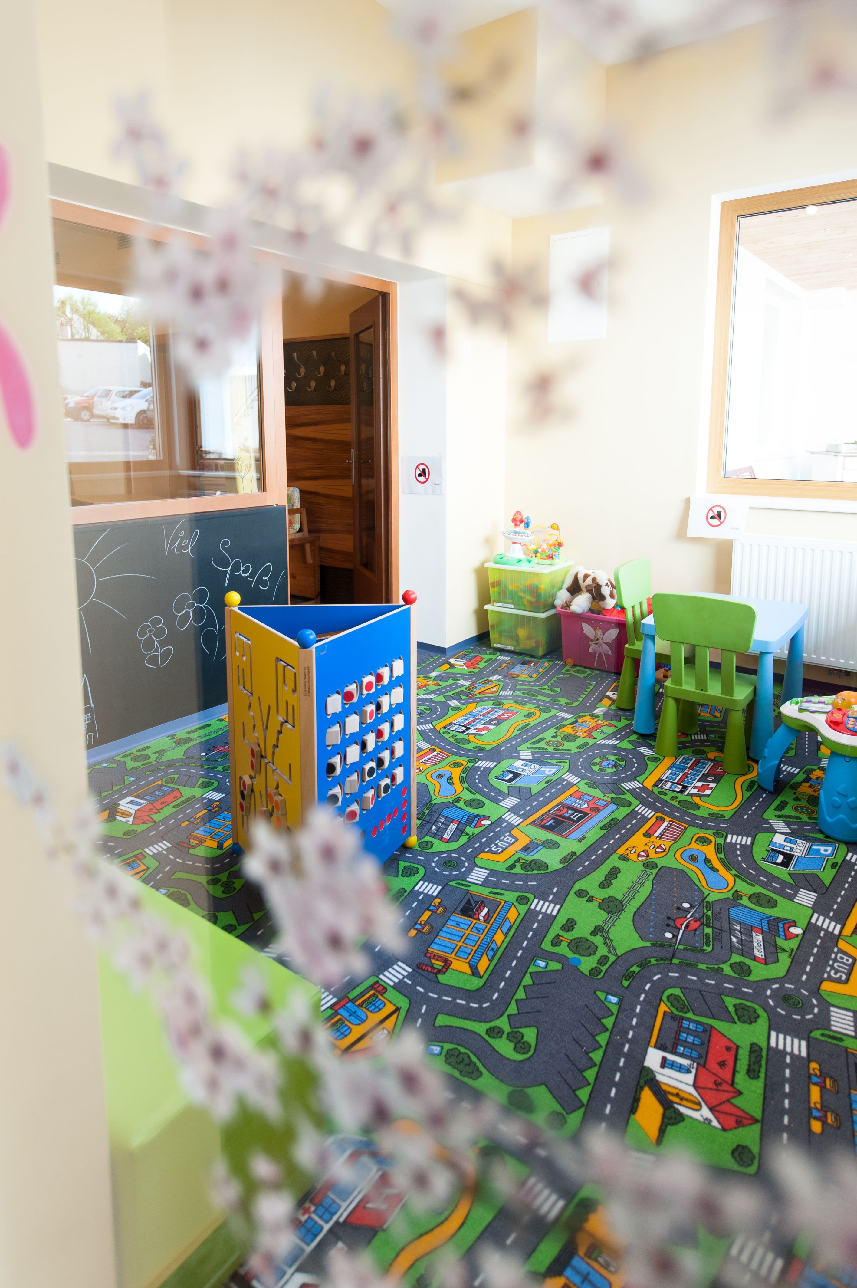 Ein bunter Kinderspielraum mit Teppich, Spielzeug und kleinen Möbeln.