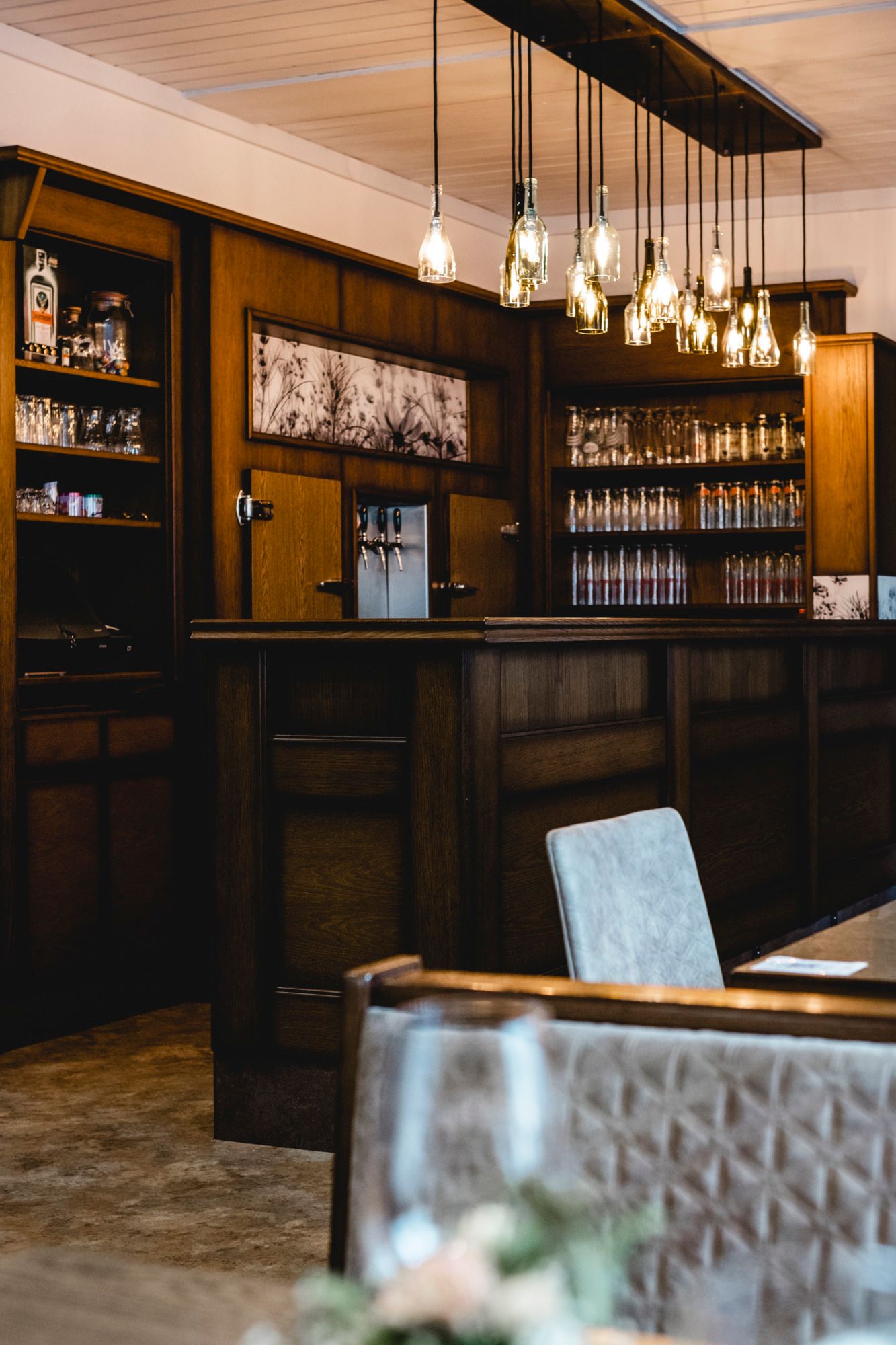 Gemütliche Bar mit Holzmöbeln und hängenden Glühbirnen.