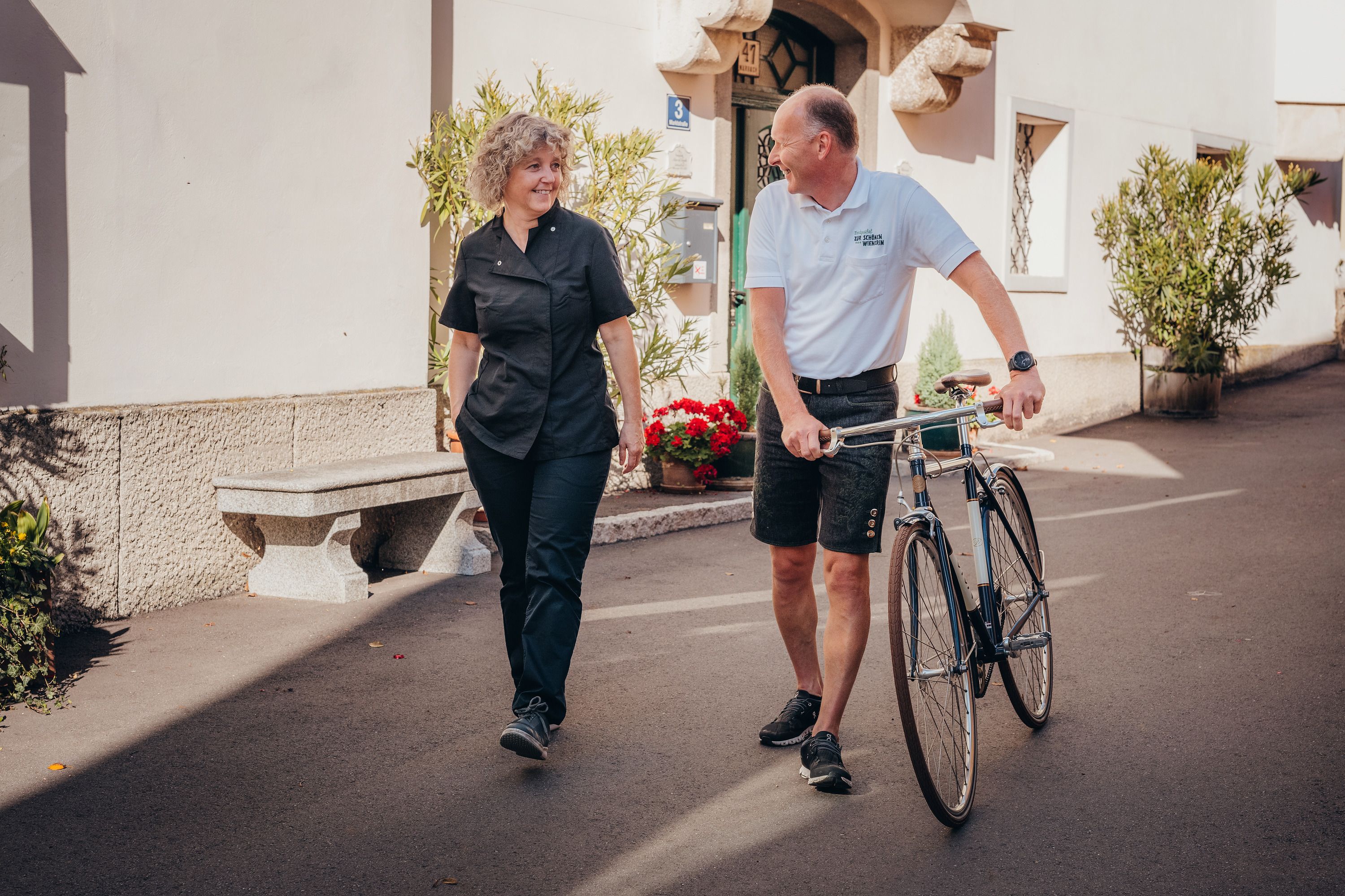 Zwei Personen unterhalten sich, während einer ein Fahrrad schiebt.