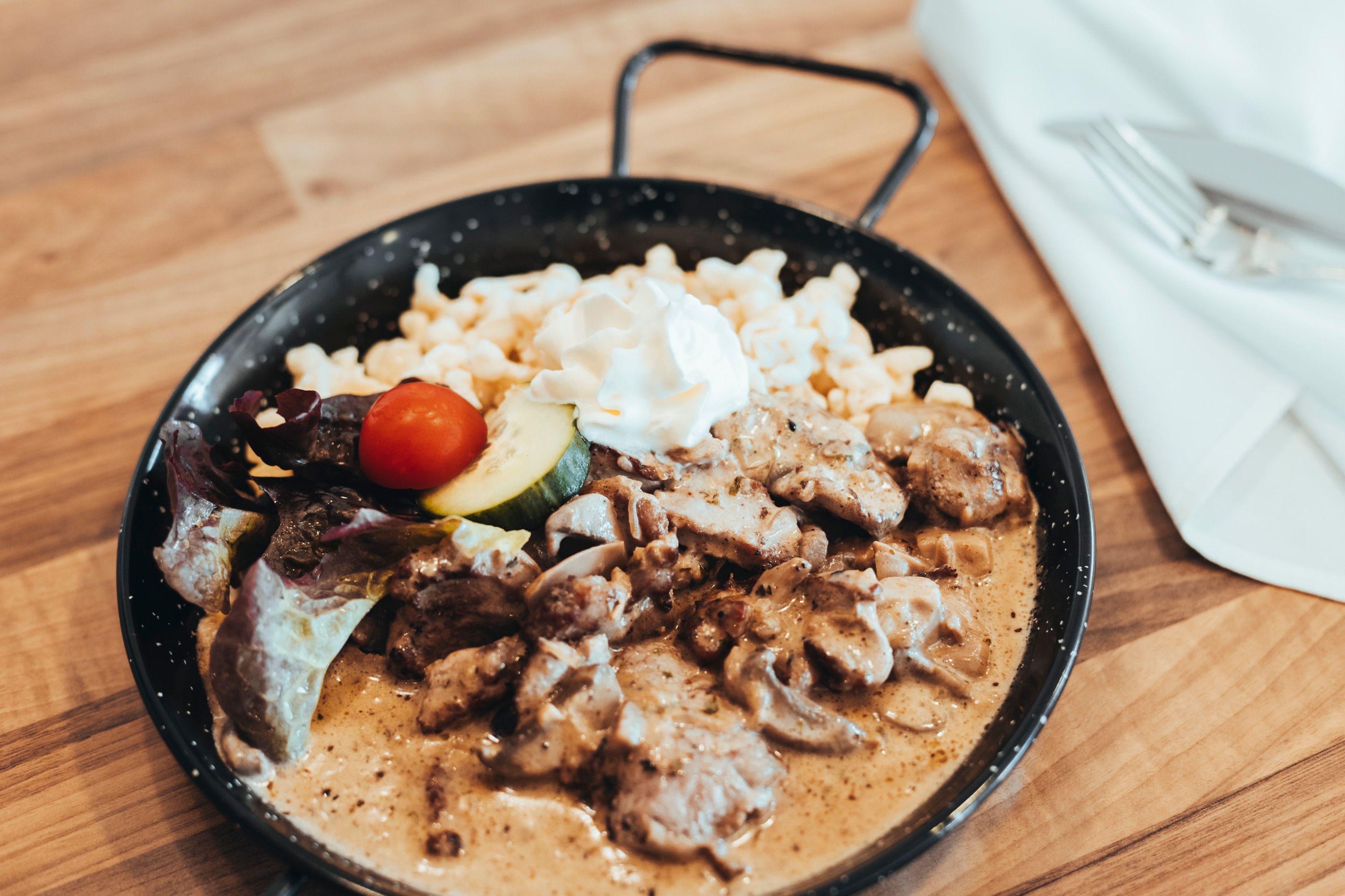 Ein Gericht in einer Pfanne mit Fleisch, Spätzle, Sahne und Gemüse.
