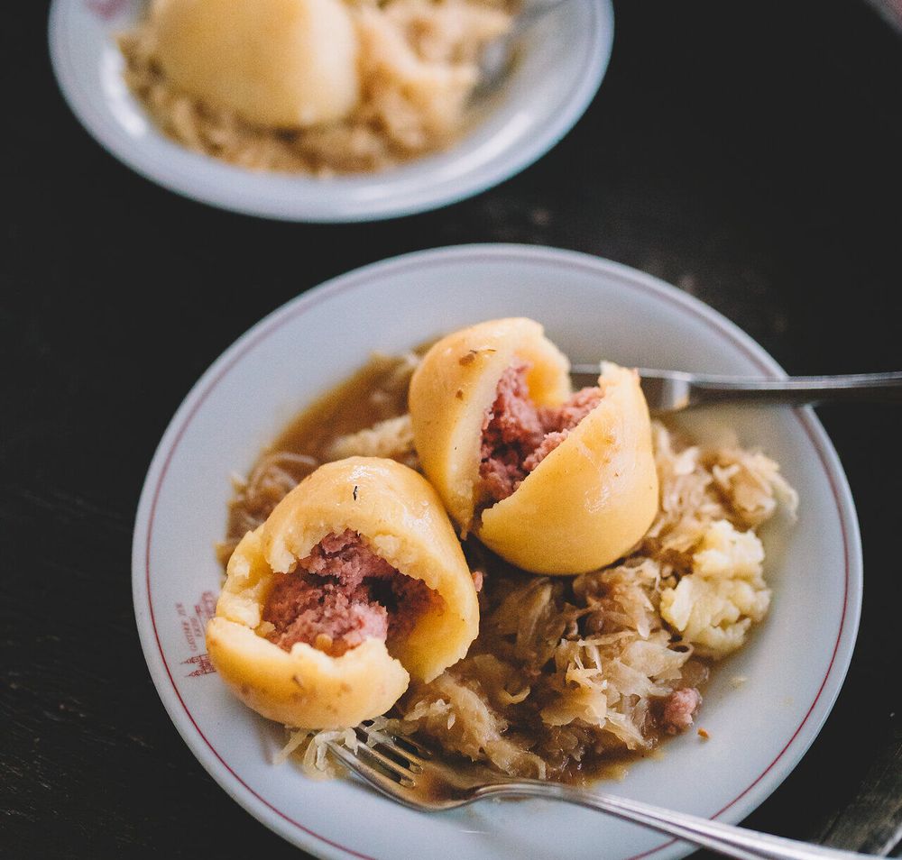 Genießen Sie die herzhaften Fleischknödel, die auf einem Bett aus sauer eingelegtem Gemüse serviert werden. Diese traditionelle Speise lädt dazu ein, die kulinarischen Köstlichkeiten der Region zu entdecken und sich in geselliger Runde zu entspannen.