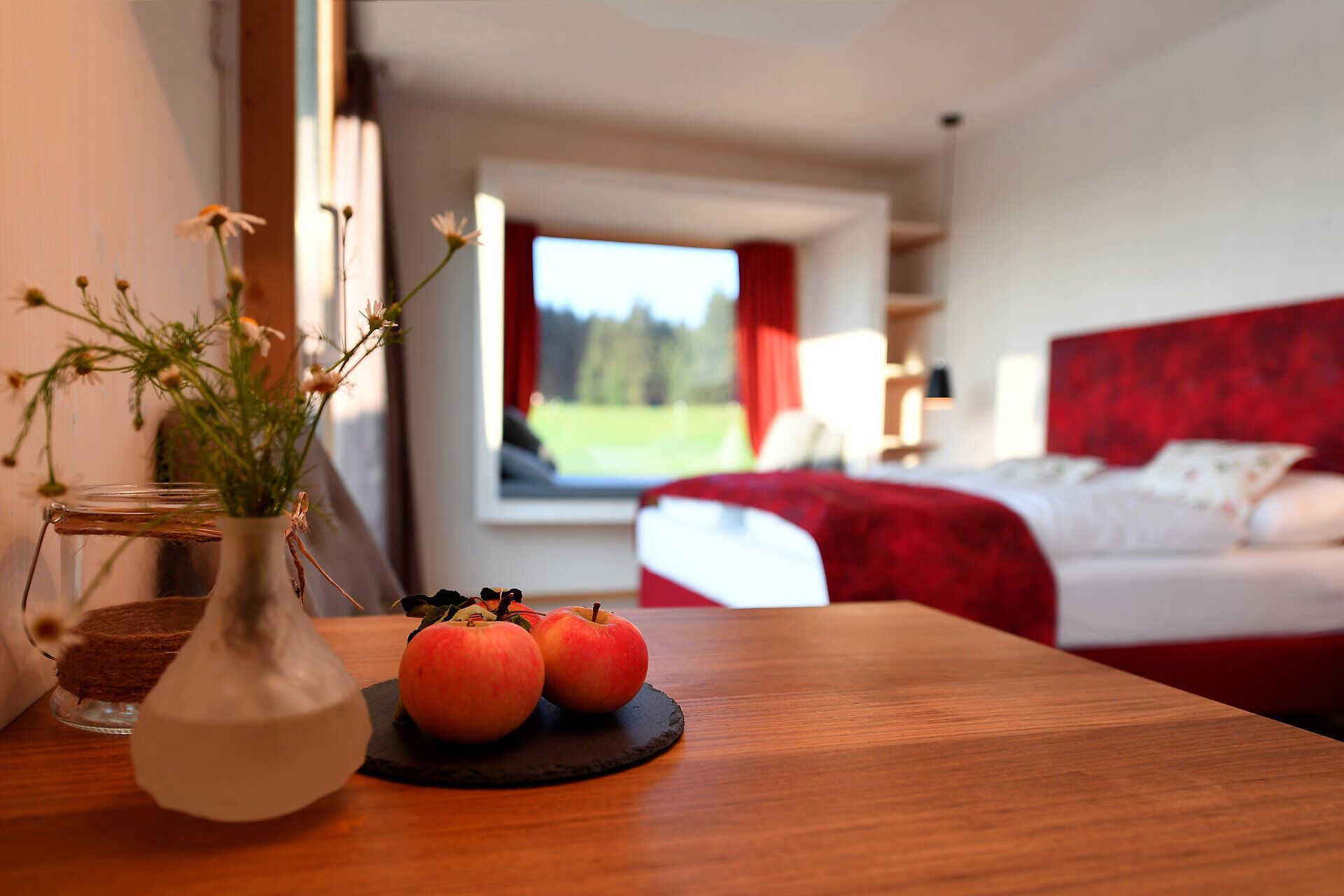 Ein einladendes Zimmer mit einem Hauch von Gemütlichkeit erwartet die Gäste. Die frischen Äpfel auf dem Tisch und die blühenden Wildblumen schaffen eine harmonische Atmosphäre, die zum Entspannen einlädt. Genießen Sie den Blick auf die malerische Landschaft und lassen Sie den Alltag hinter sich.