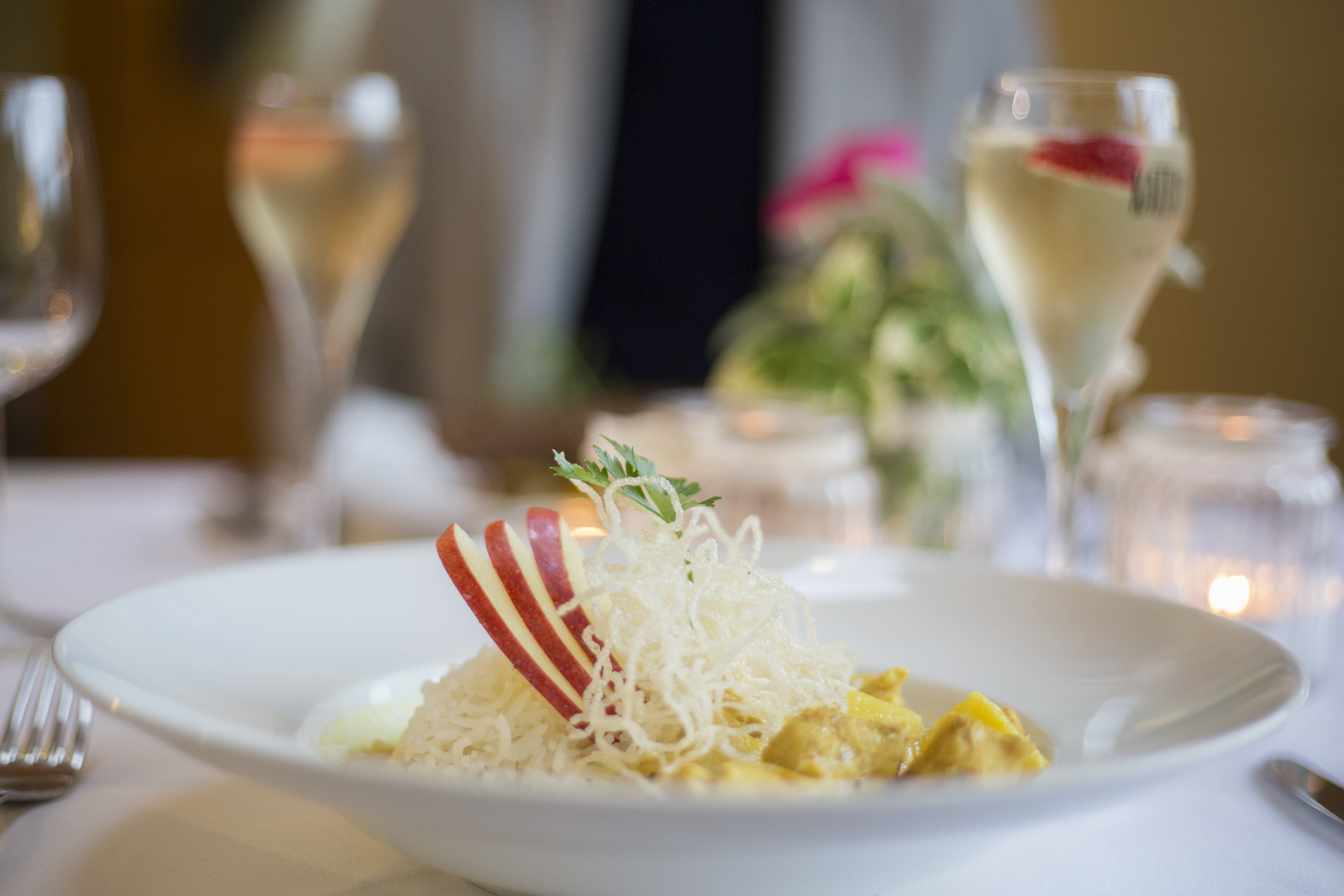 Ein Teller mit Reis, Apfelscheiben und einer Garnitur auf einem gedeckten Tisch.
