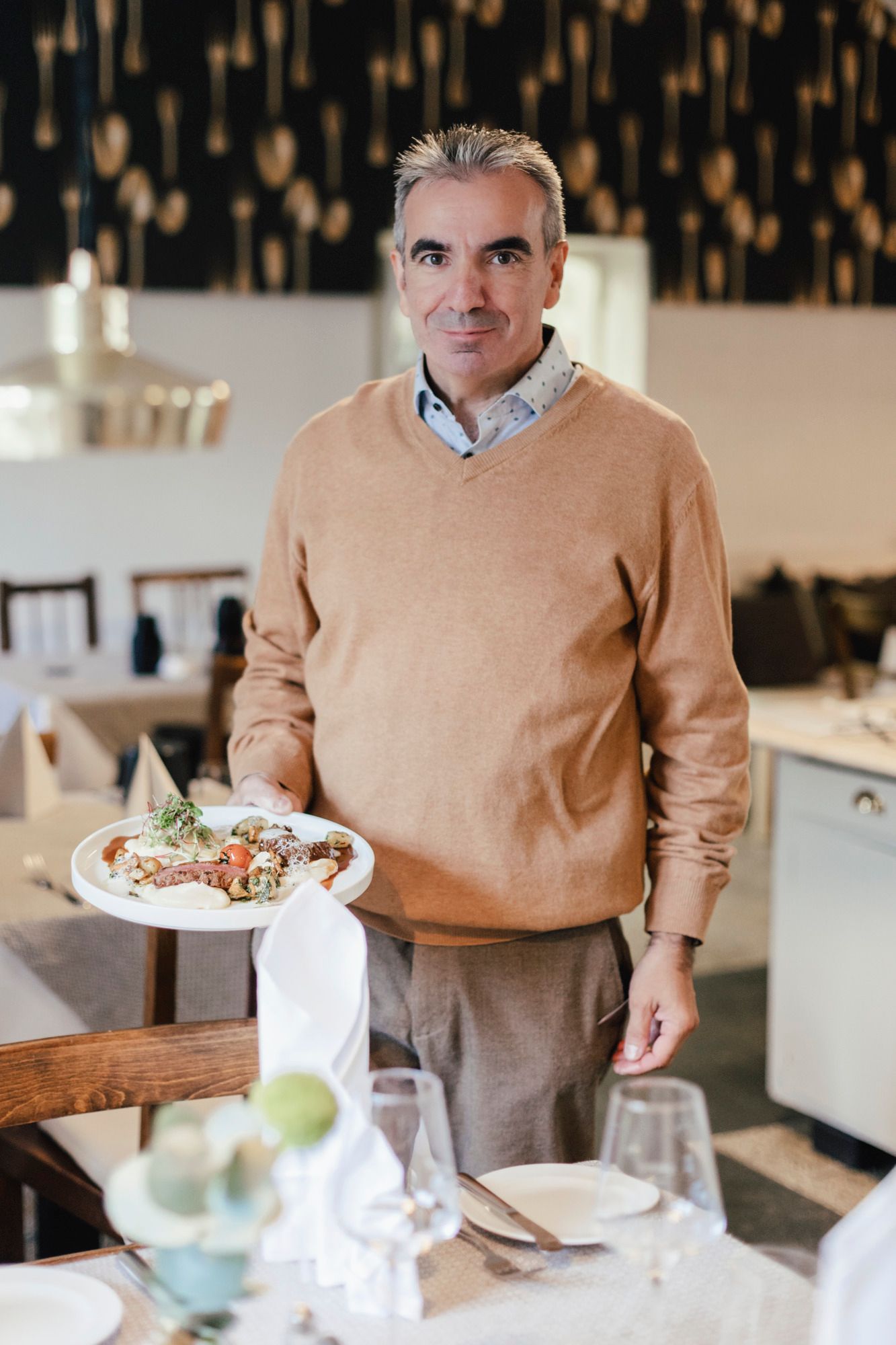 Ein Mann in einem Restaurant hält einen Teller mit Essen in der Hand.