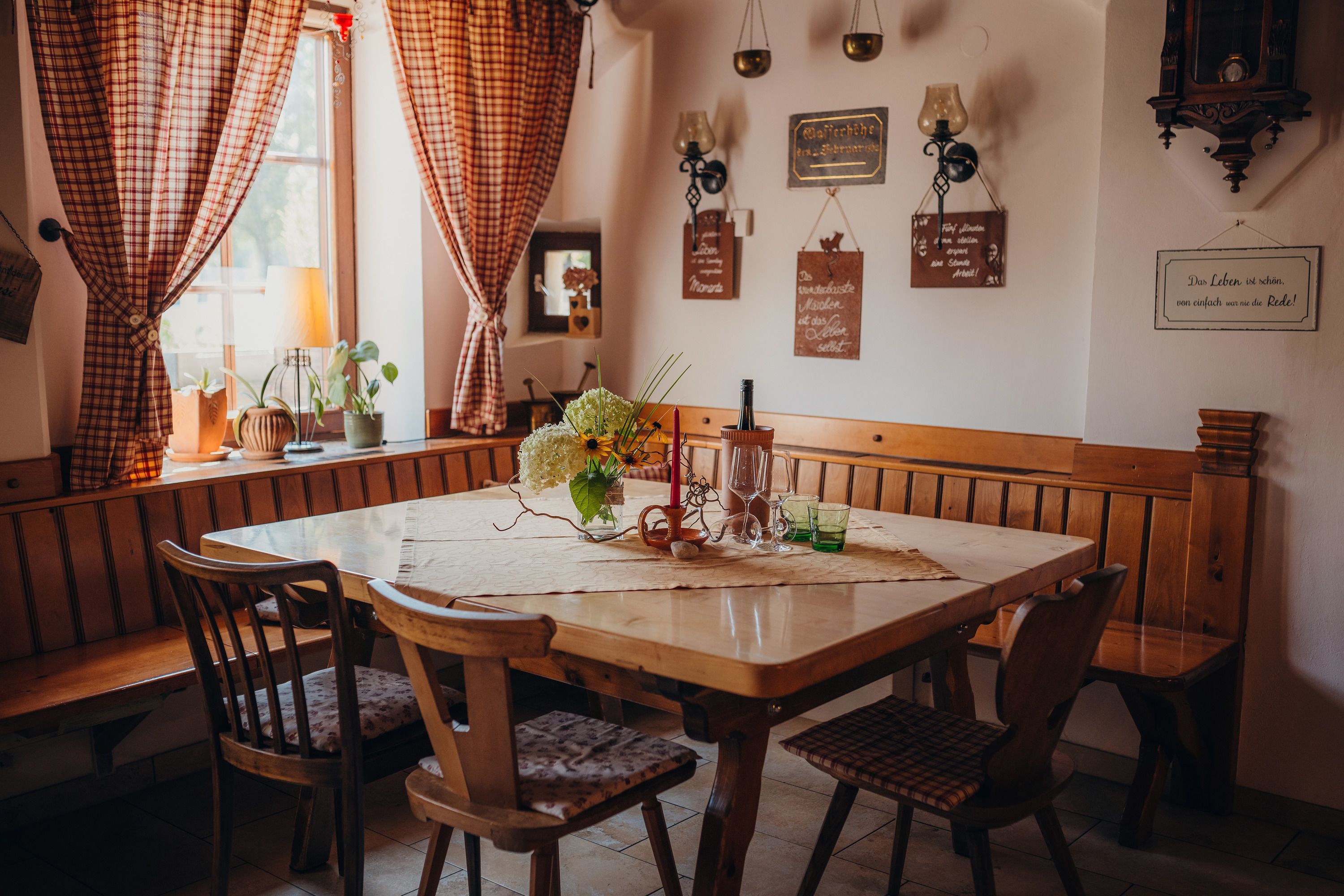Gemütliches Gastzimmer mit Holztisch, Stühlen und dekorativen Elementen an den Wänden.
