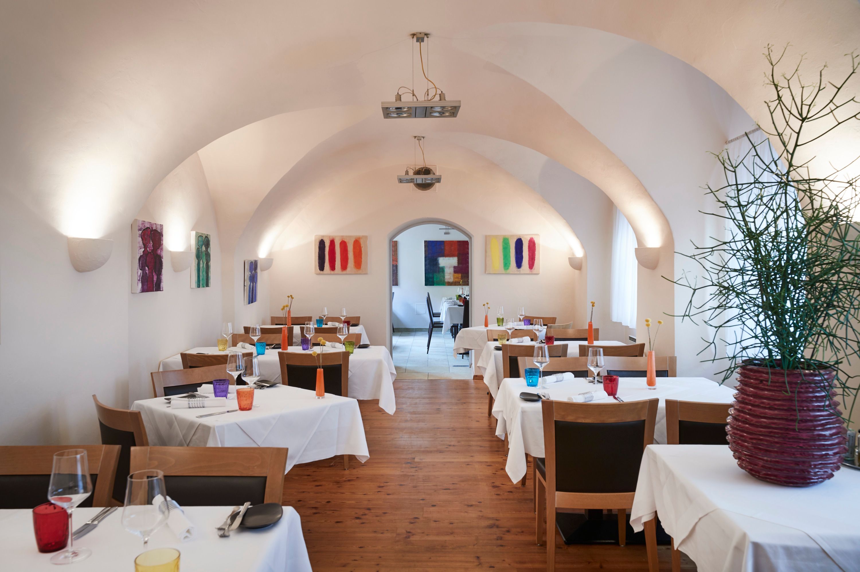 Ein elegantes Restaurant mit gewölbter Decke, weißen Tischdecken und bunter Dekoration.