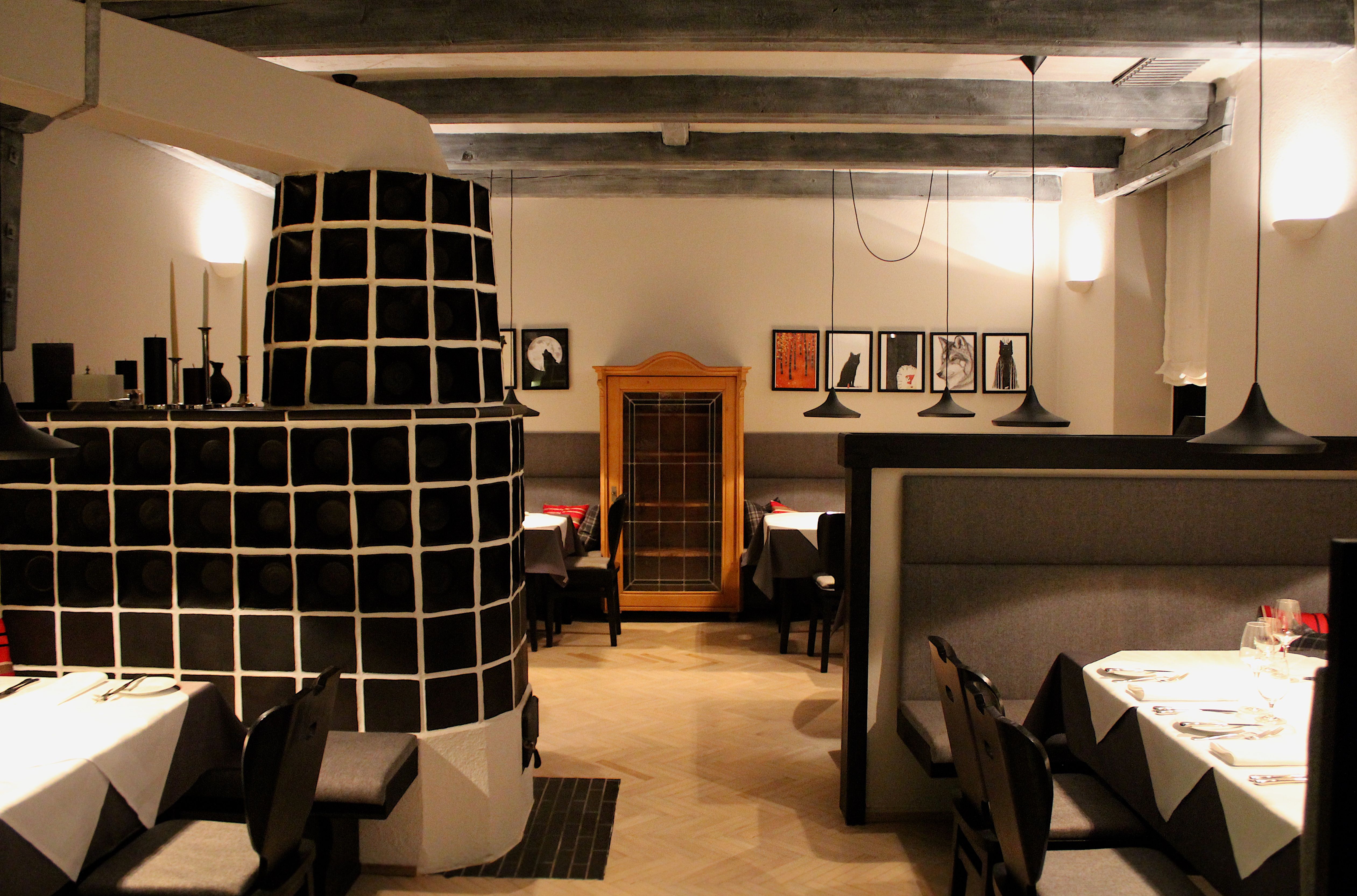 Restaurant innen, schwarzer Kachelofen, Tische mit weißer Tischwäsche
