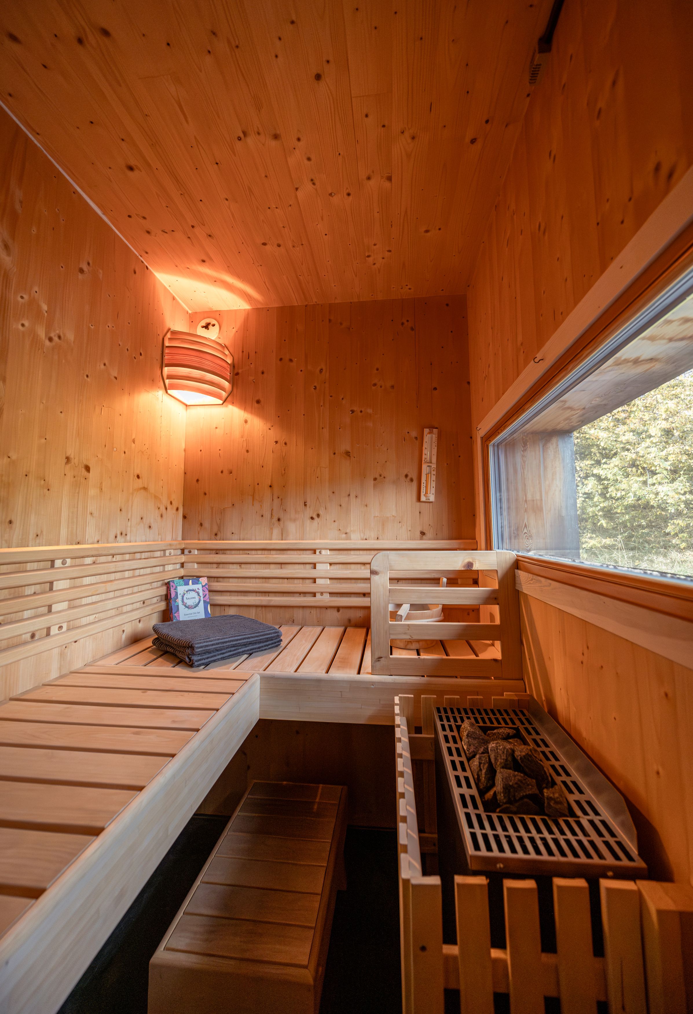 Innenansicht einer Holzsauna mit Bänken, Handtuch und Fenster.