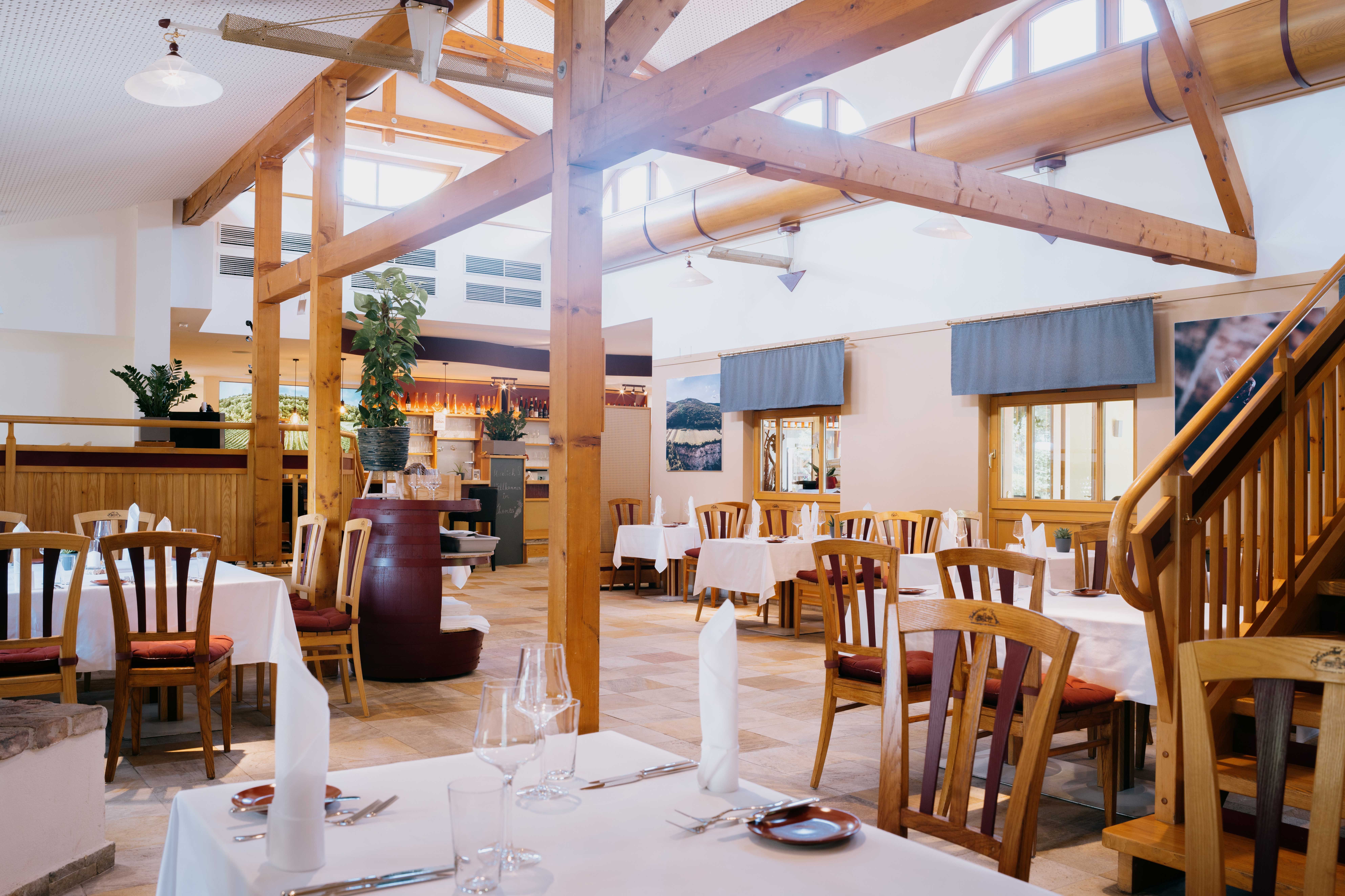 Innenansicht einer Gaststube mit Holzelementen und gedeckten Tischen.