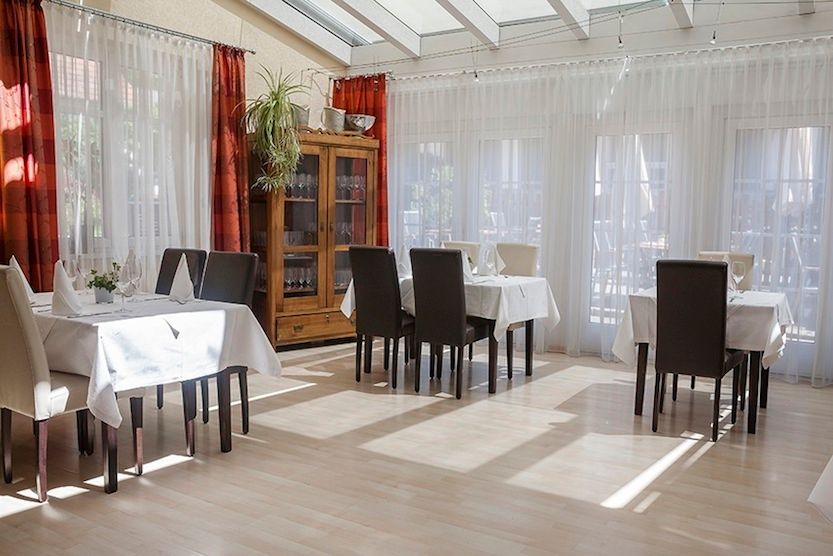 Innenansicht eines hellen Restaurants mit gedeckten Tischen und Stühlen.