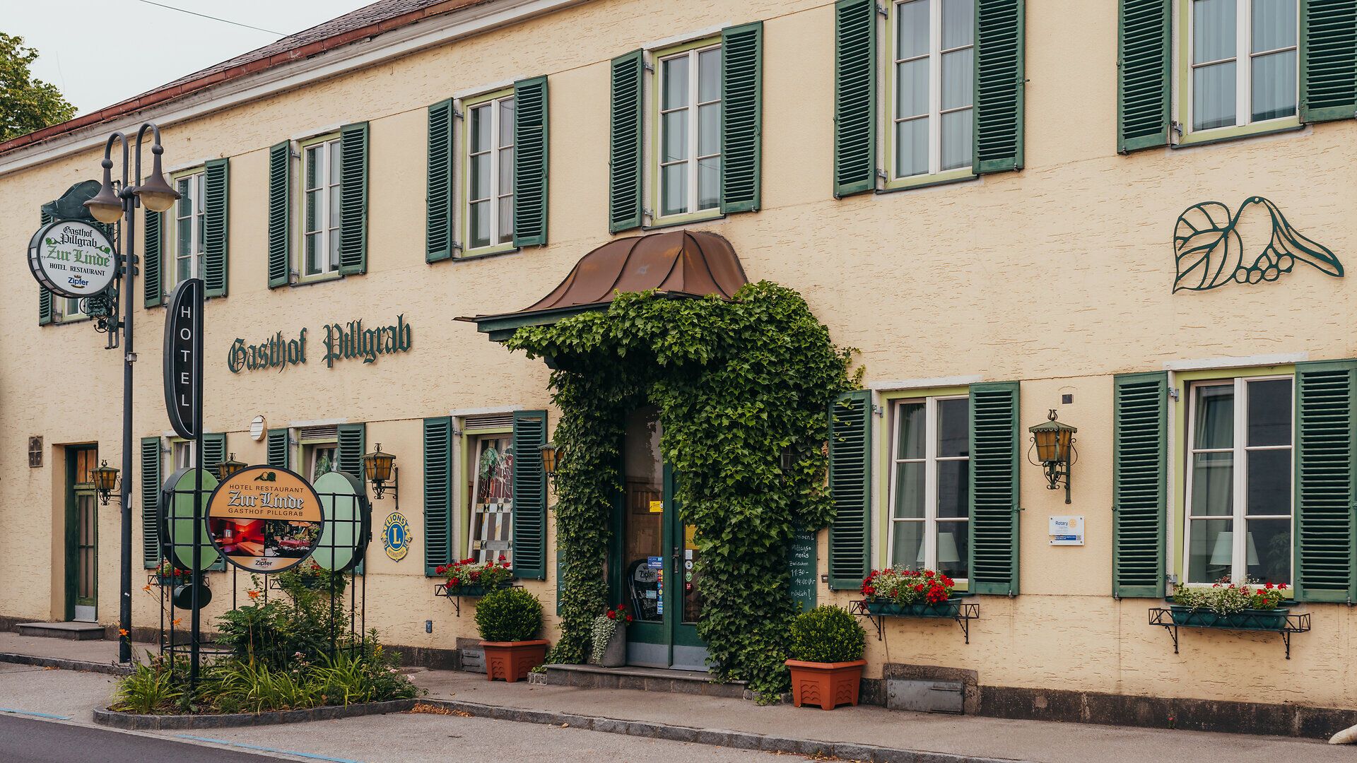Umgeben von üppigem Grün und blühenden Pflanzen strahlt der Gasthof Pillgrab eine einladende Atmosphäre aus. Die charmante Fassade und die liebevoll gestalteten Fensterläden laden dazu ein, die regionale Gastfreundschaft zu genießen und die Schönheit des Mostviertels zu entdecken.