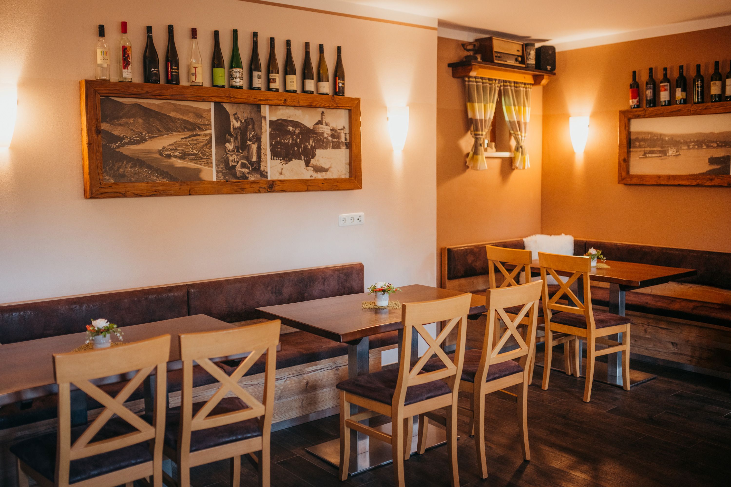 Gemütliches Restaurant mit Holzmöbeln, Weinflaschen und historischen Fotos.