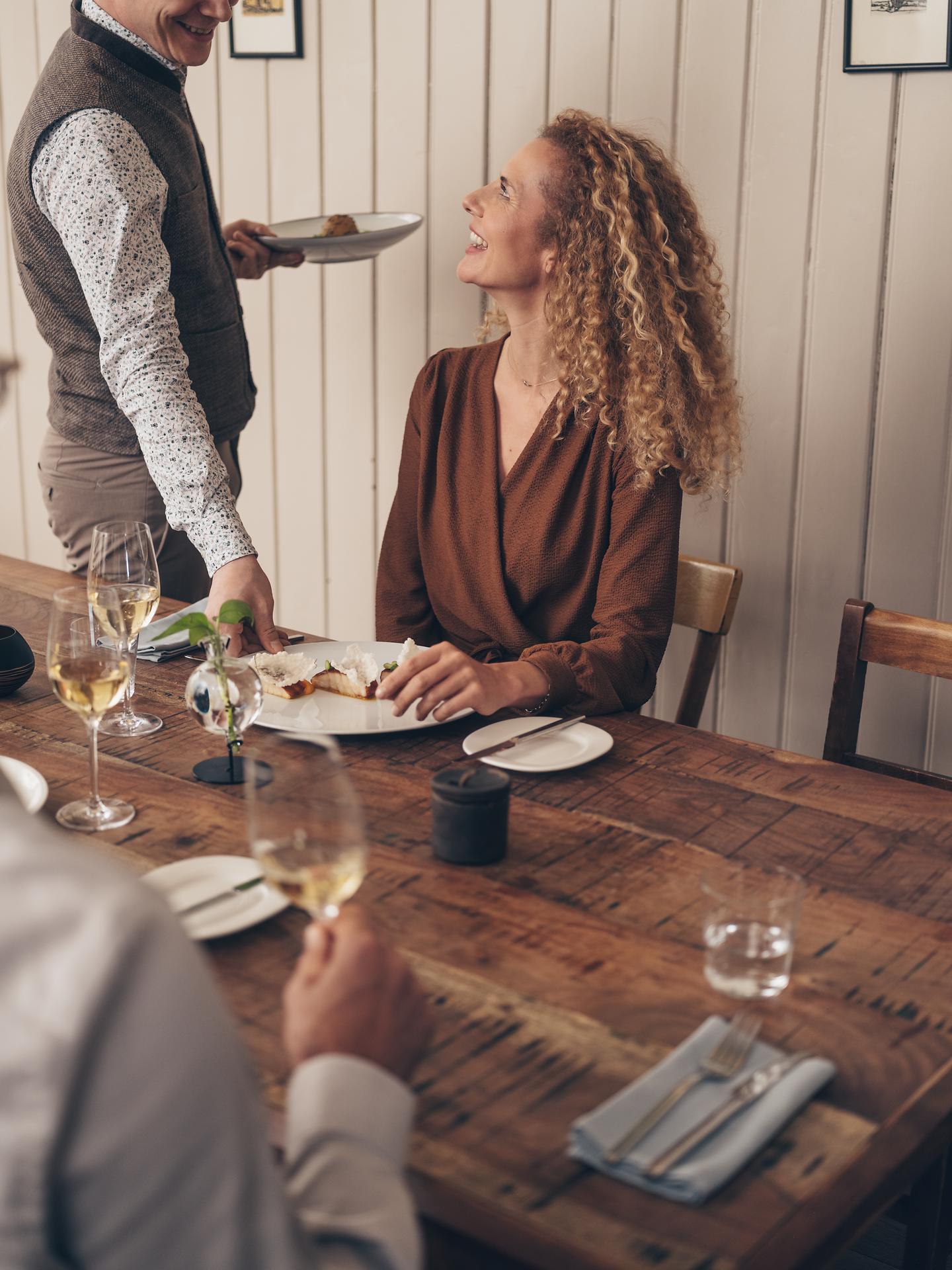 In einem einladenden Wirtshaus genießen Gäste ein köstliches gegrilltes Störfilet, umgeben von einer warmen, geselligen Atmosphäre. Die liebevoll angerichteten Speisen und die fröhlichen Gespräche schaffen ein unvergessliches kulinarisches Erlebnis inmitten der charmanten Wirtshauskultur Niederösterreichs.