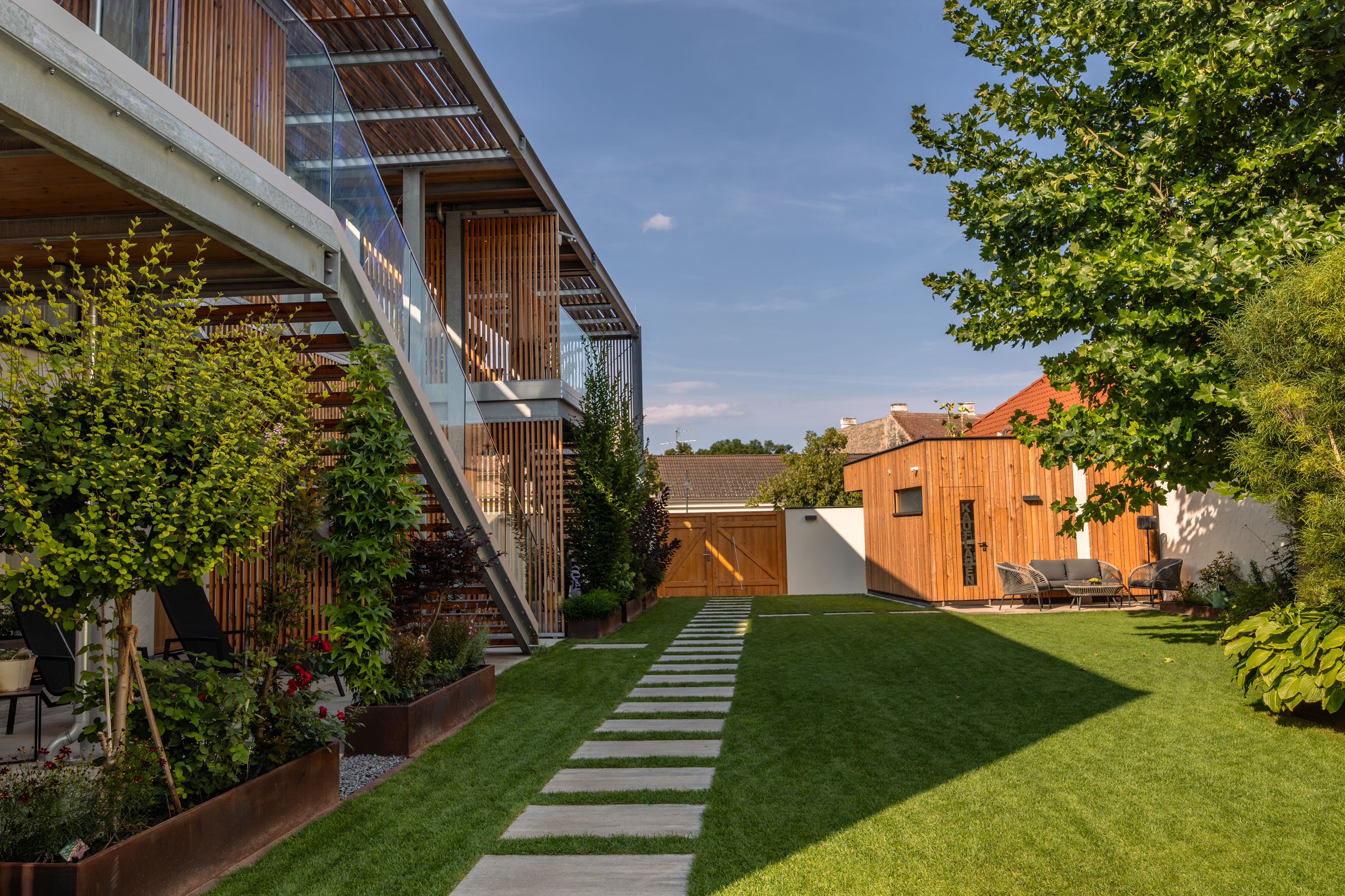 Modern apartment complex with garden and wood paneling.