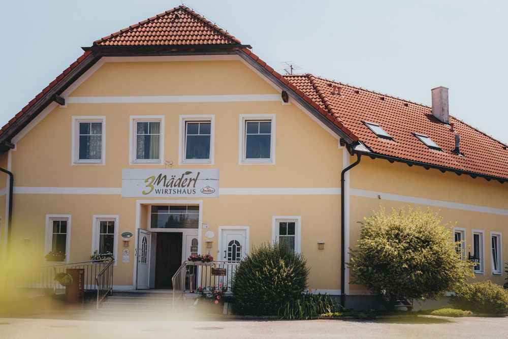 Gelbes Gebäude mit rotem Dach und Schild '3 Mädel Wirtshaus'.