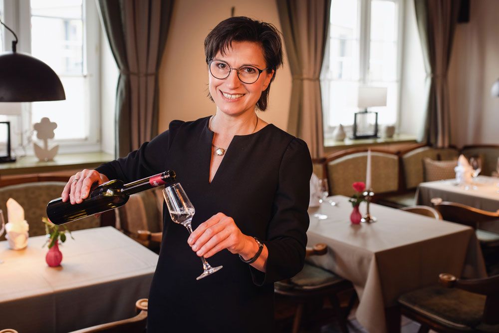 Eine Frau in einem Restaurant schenkt Wein in ein Glas ein.