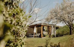 Inmitten einer malerischen Landschaft steht eine moderne Hütte, umgeben von blühenden Bäumen und saftigem Grün. Die einladenden Liegen laden dazu ein, die frische Bergluft zu genießen und die Ruhe der Natur zu erleben. Hier wird der Sommer in den Bergen zum unvergesslichen Erlebnis.
