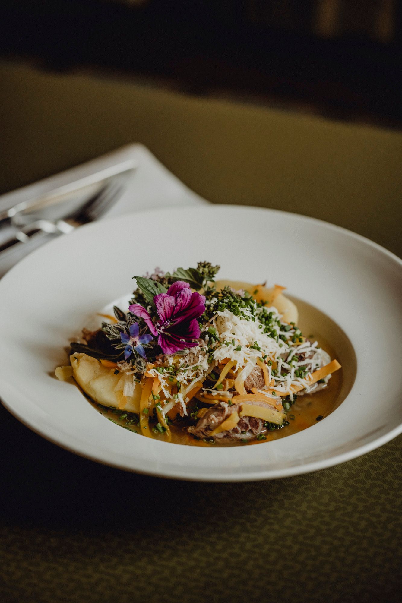 A plate of root meat garnished with edible flowers and herbs.