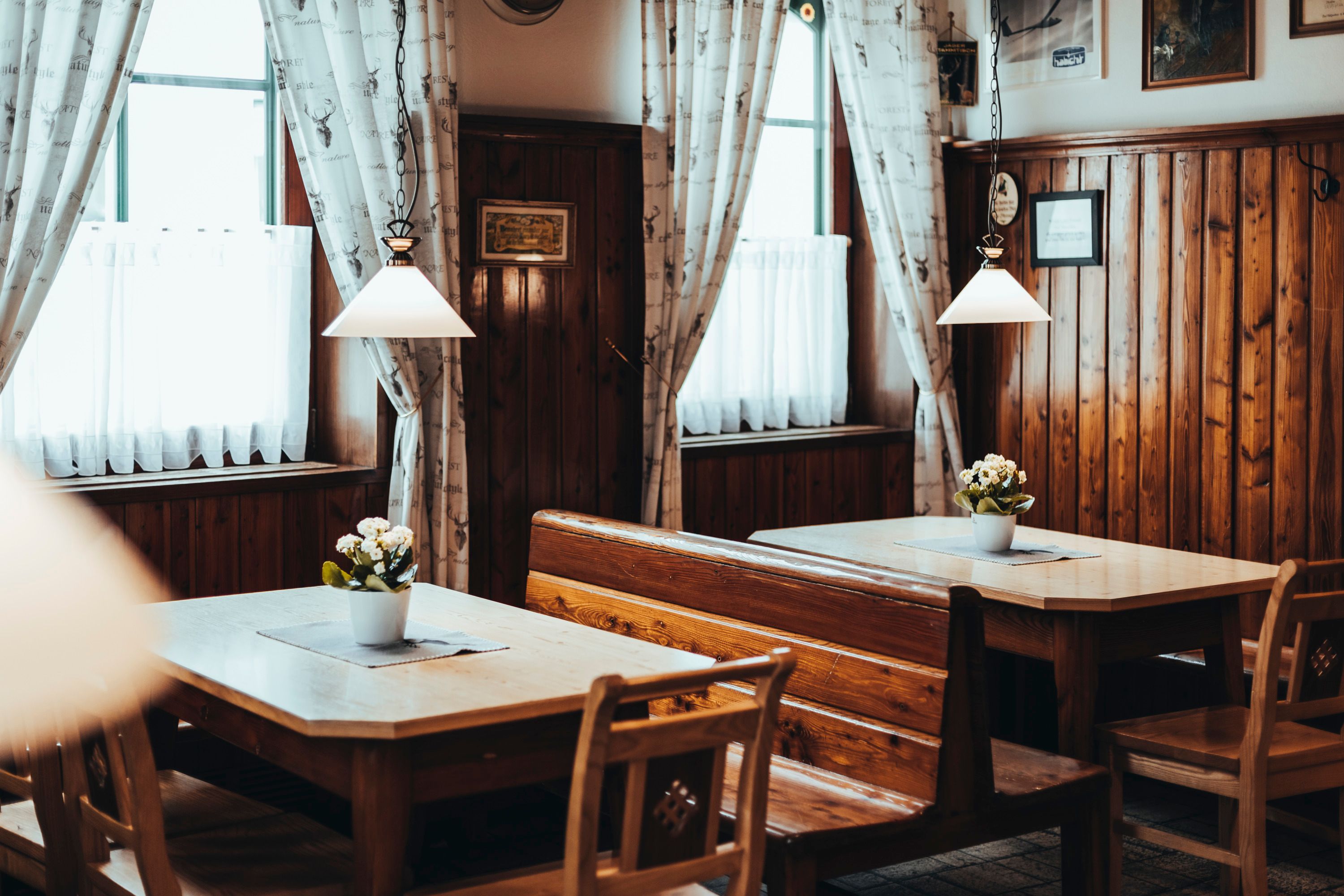 Gemütliches, rustikales Restaurant mit Holzmöbeln und Blumen auf den Tischen.