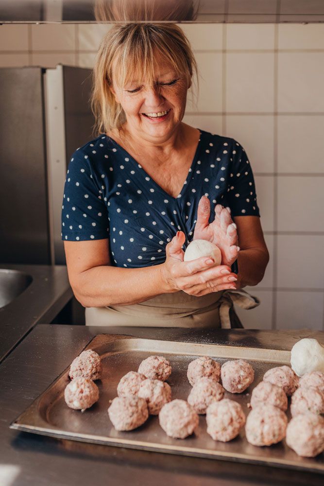 Frau formt Teigbällchen in einer Küche.