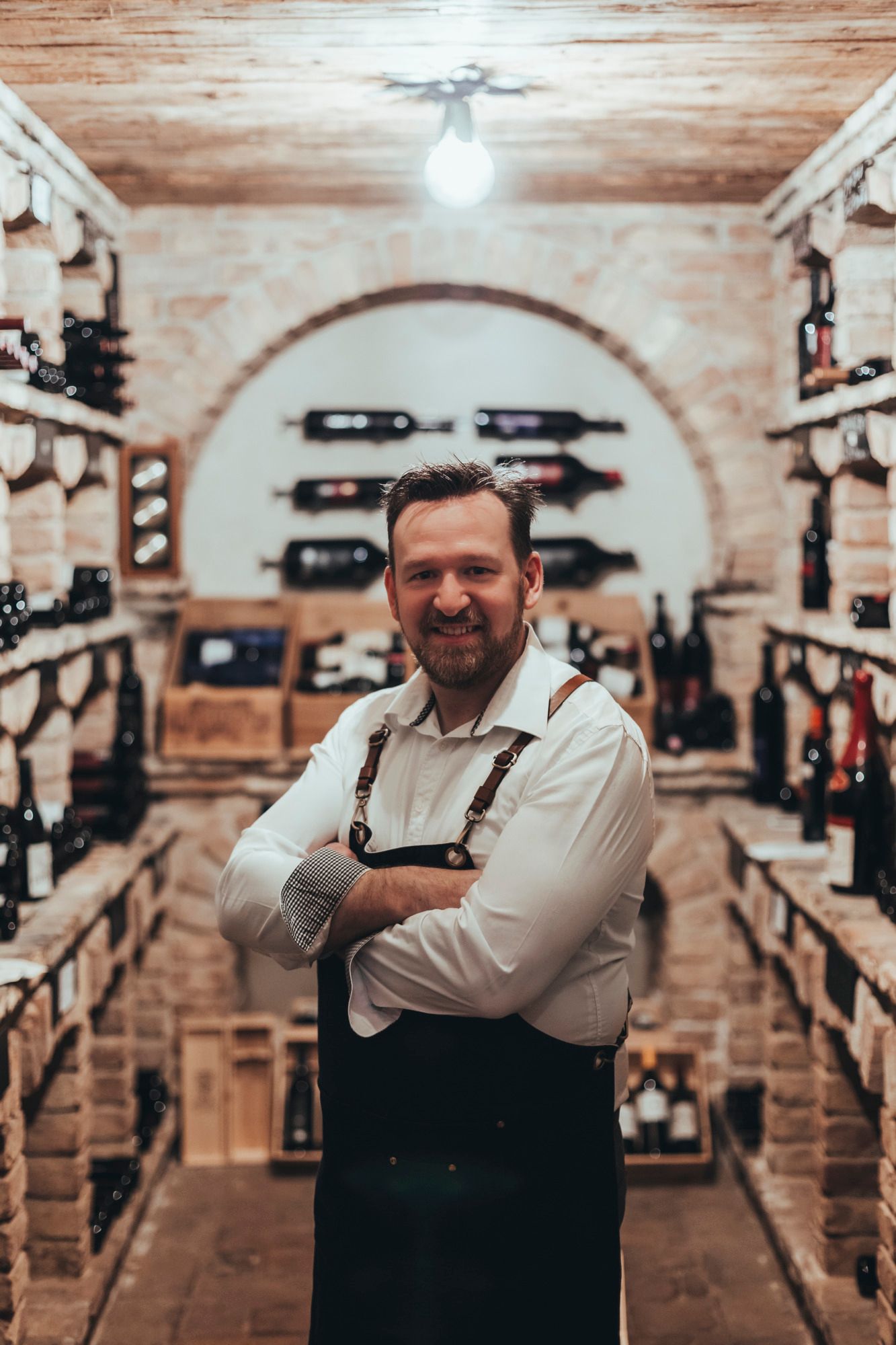 Ein Mann in einem Weinkeller mit Regalen voller Weinflaschen.