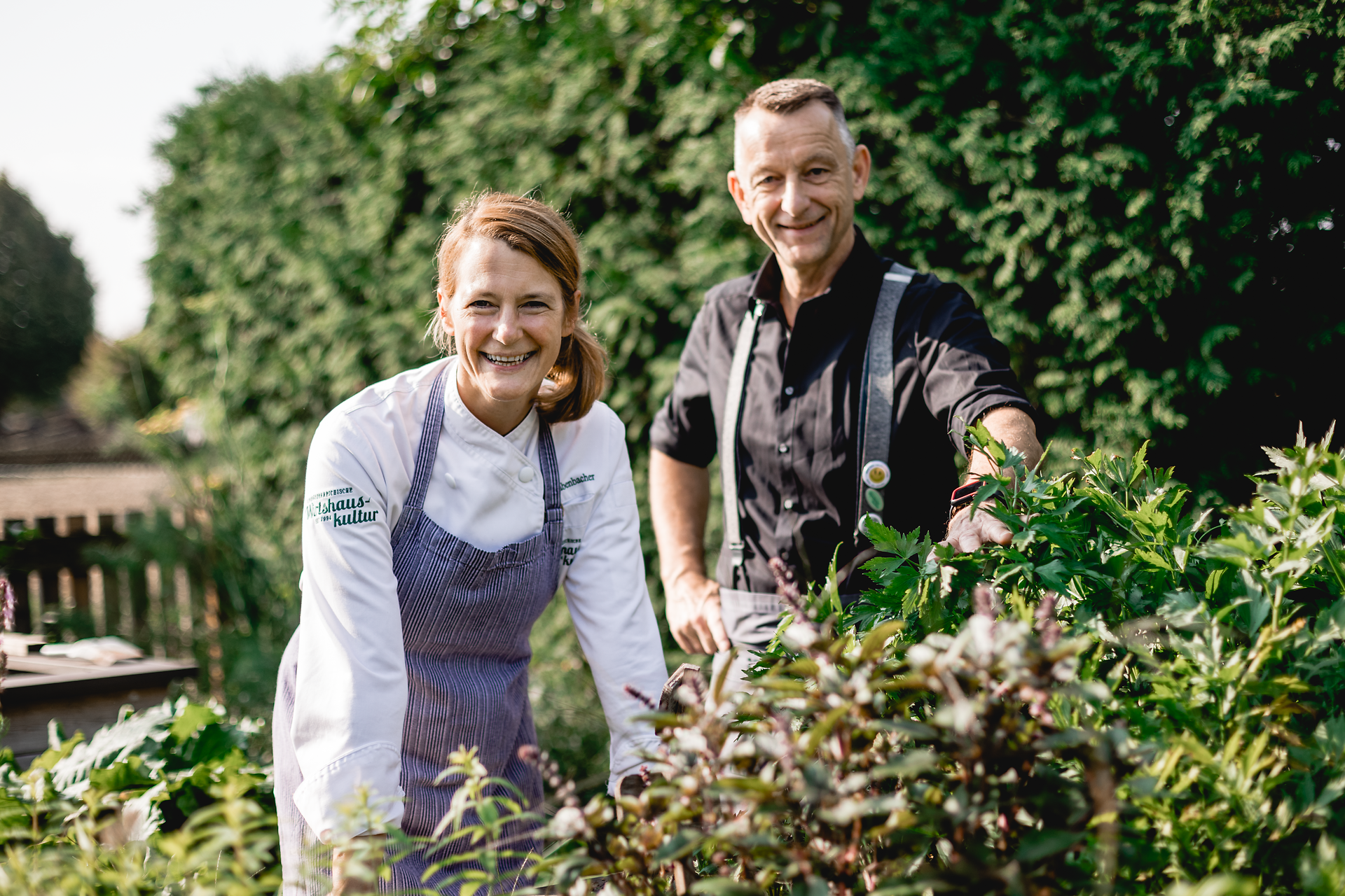 In einem liebevoll gepflegten Gemüsegarten, umgeben von üppigem Grün, lächeln die Wirtsleute herzlich. Frische Kräuter und Gemüse sprießen hier, bereit, die Gäste mit regionalen Köstlichkeiten zu verwöhnen. Ein Ort, an dem die Wirtshauskultur lebendig wird und die Natur zum Genießen einlädt.