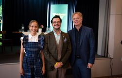 Kira Schinko, Hartmuth Rameder und Michael Duscher (v. l. n. r.) stehen lächelnd gemeinsam vor einer Bühne.