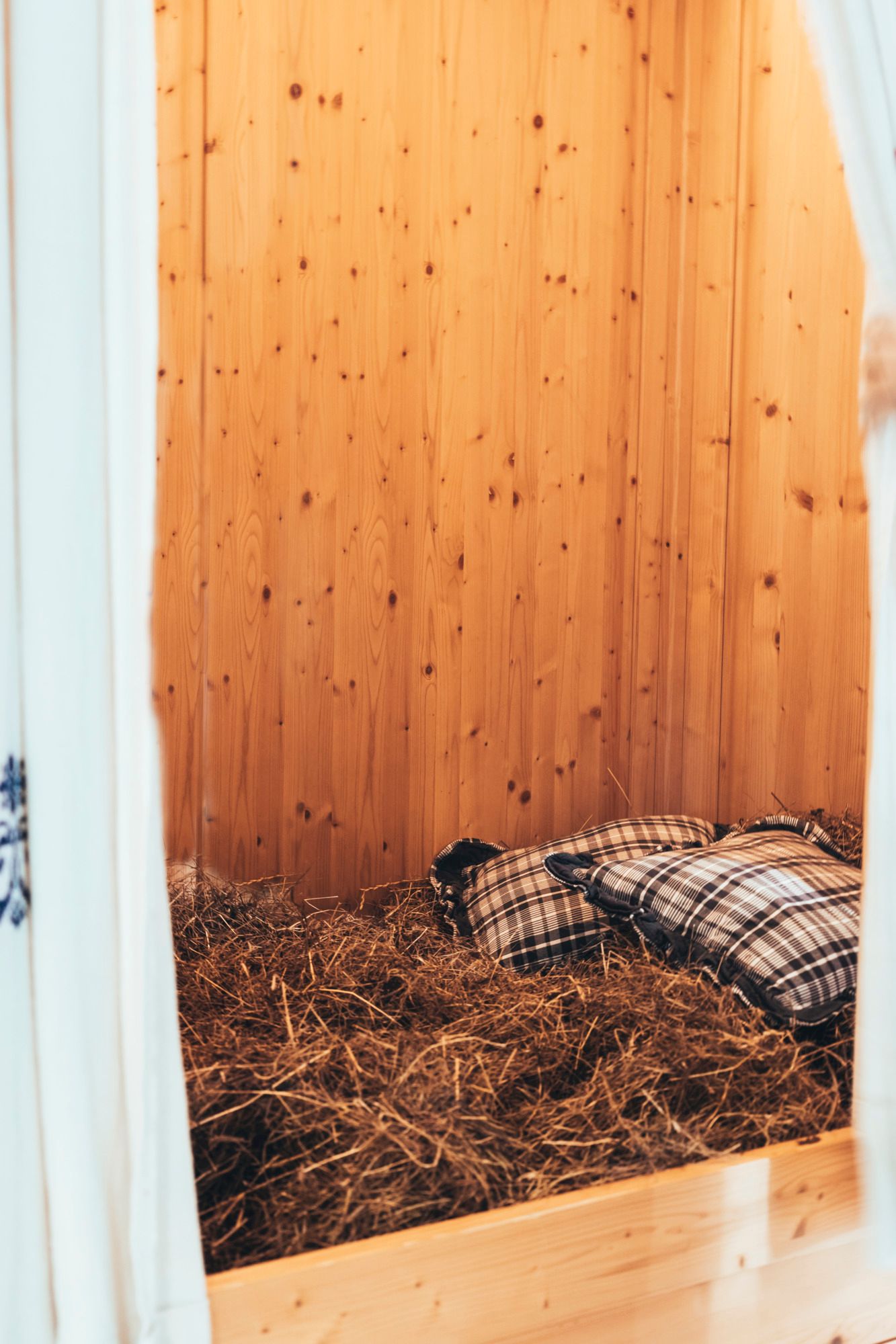 Ein gemütliches Heu-Bett mit karierten Kissen in einem Raum mit Holzwänden.