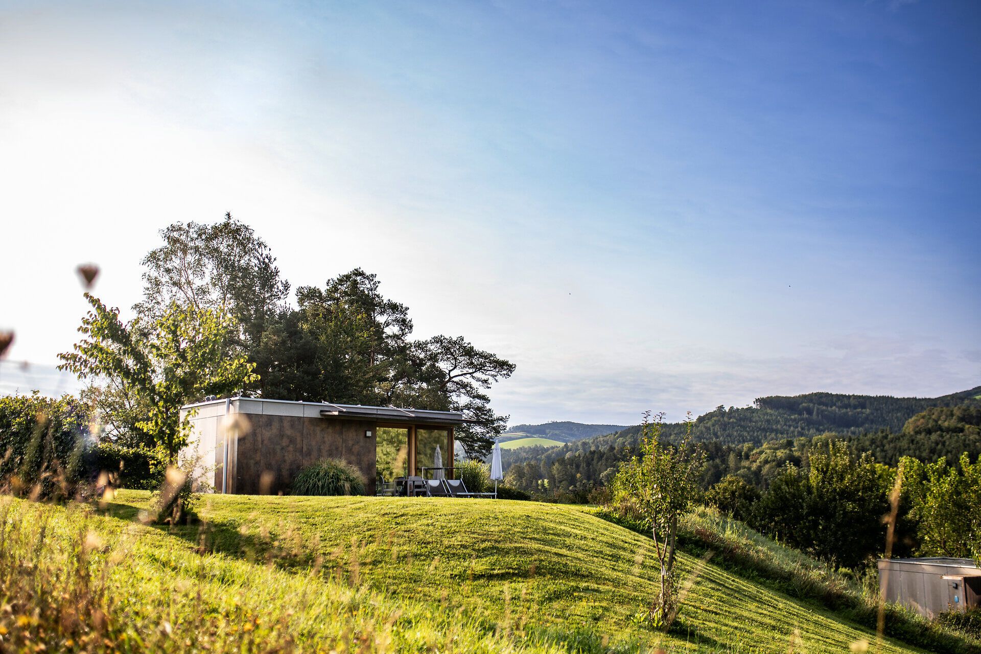 Inmitten sanfter Hügel und üppiger Wiesen strahlt die Ruhe der Natur. Ein modernes Häuschen lädt dazu ein, die atemberaubende Aussicht auf die umliegenden Berge zu genießen. Hier, wo die frische Luft und das sanfte Licht des Morgens harmonisch zusammenkommen, wird jeder Moment zum unvergesslichen Erlebnis.