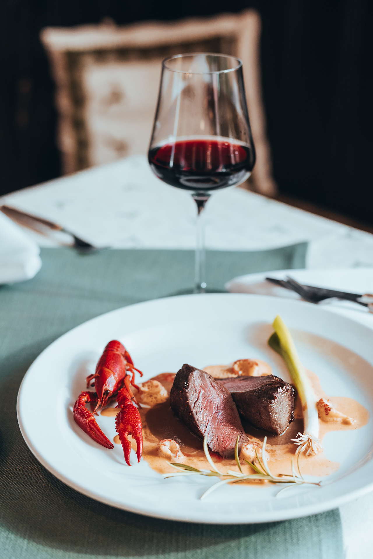 Ein köstliches Gericht aus zartem Rehfleisch, begleitet von einem frisch zubereiteten Flusskrebs, lädt zu einem genussvollen Abend ein. Ein Glas tiefroter Wein rundet das Erlebnis ab und verspricht unvergessliche Momente in der Wirtshauskultur Niederösterreich.