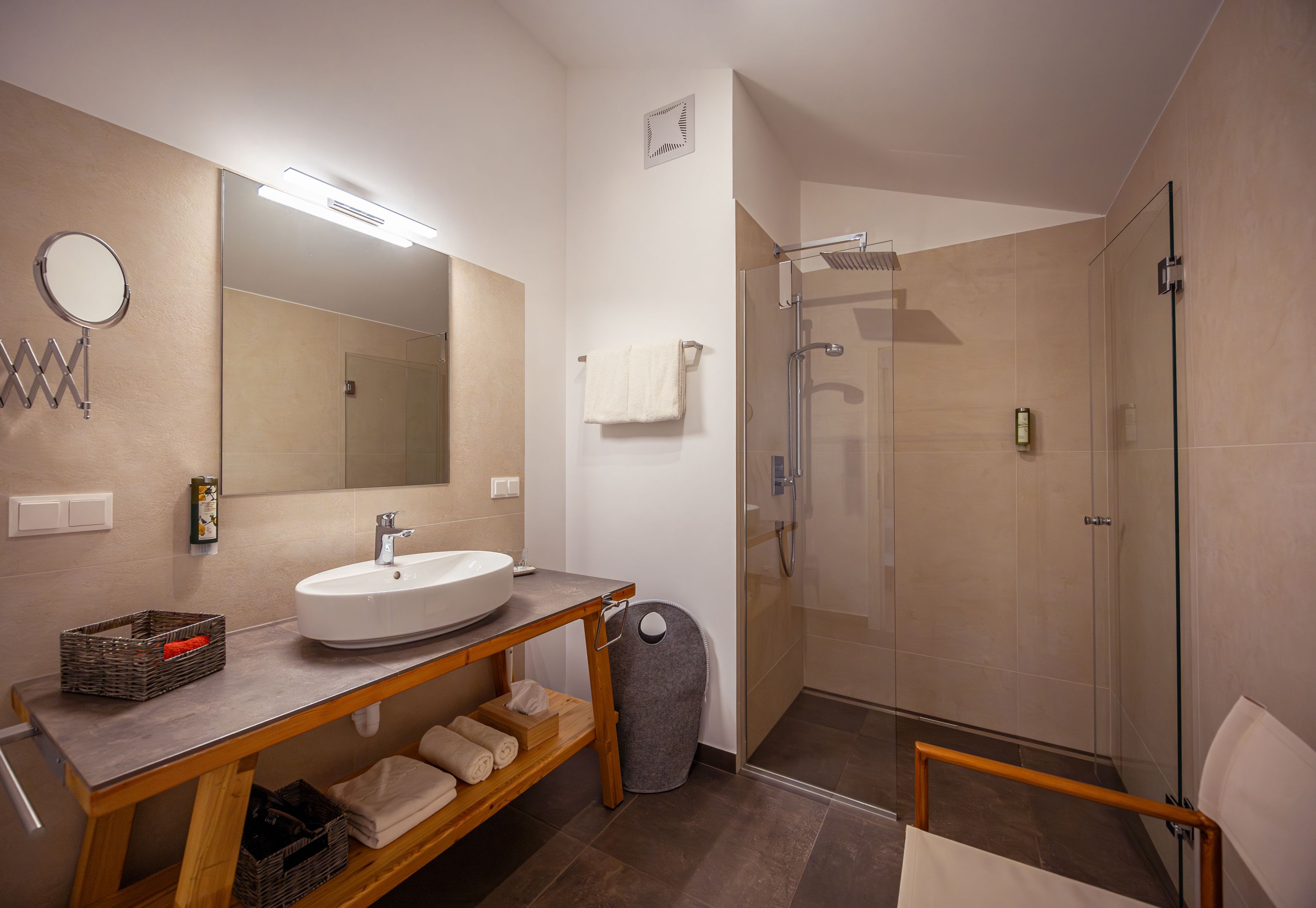 Modern bathroom with washbasin, mirror, shower and towels.