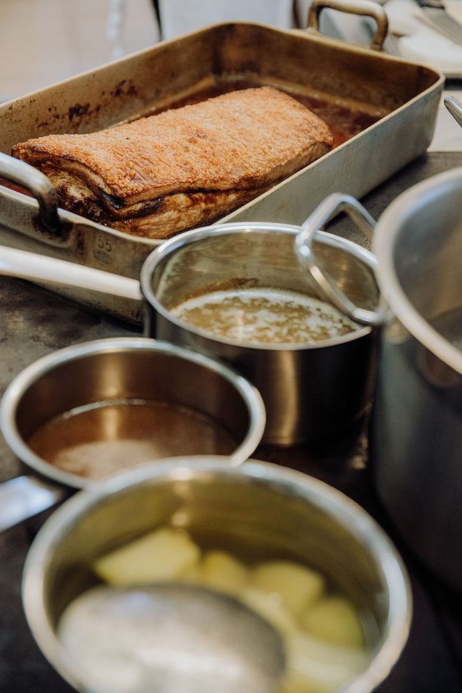 Braten in einer Auflaufform mit Töpfen auf einem Herd in der Küche.