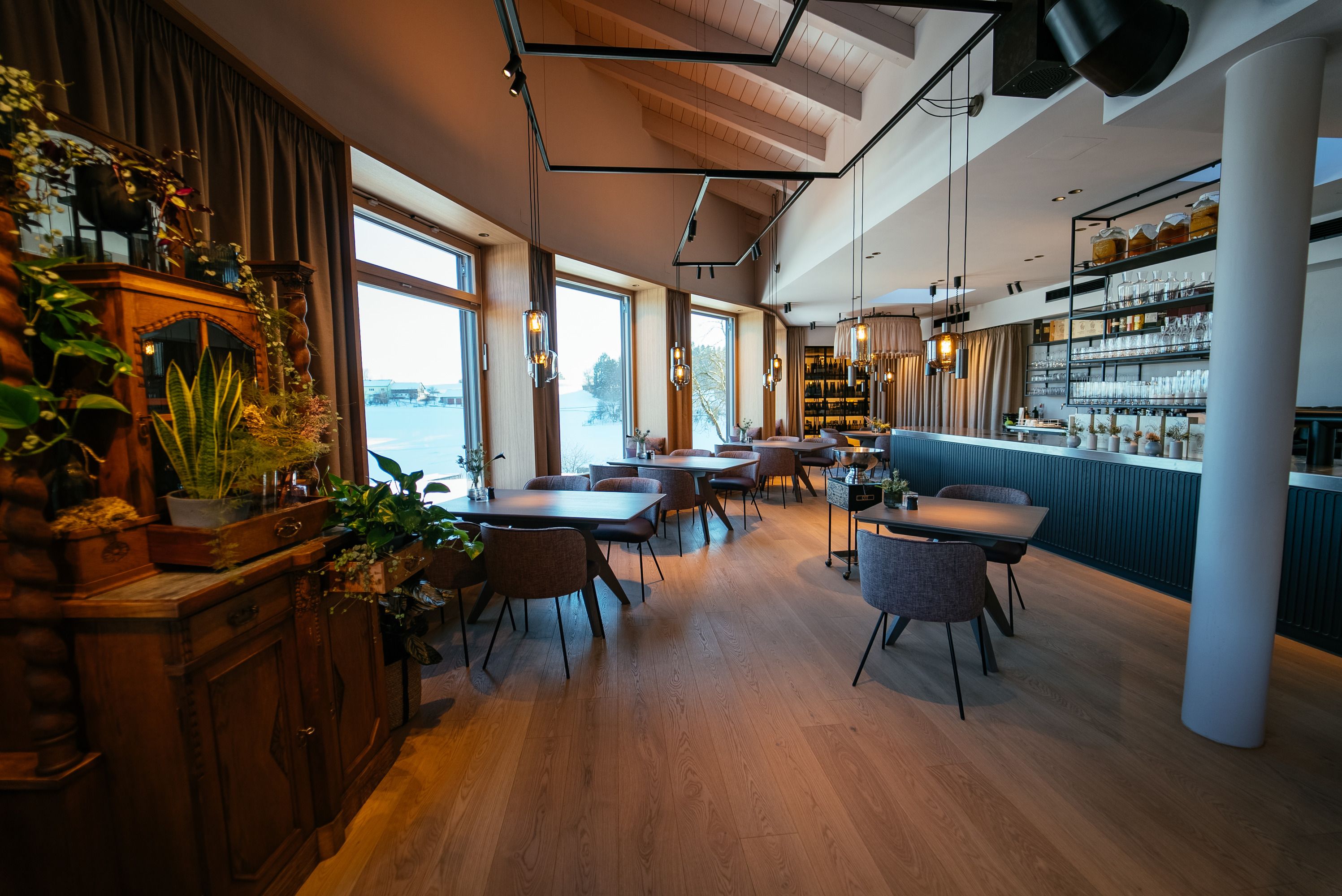 Elegantes Restaurant mit Holzboden, großen Fenstern und stilvoller Einrichtung.