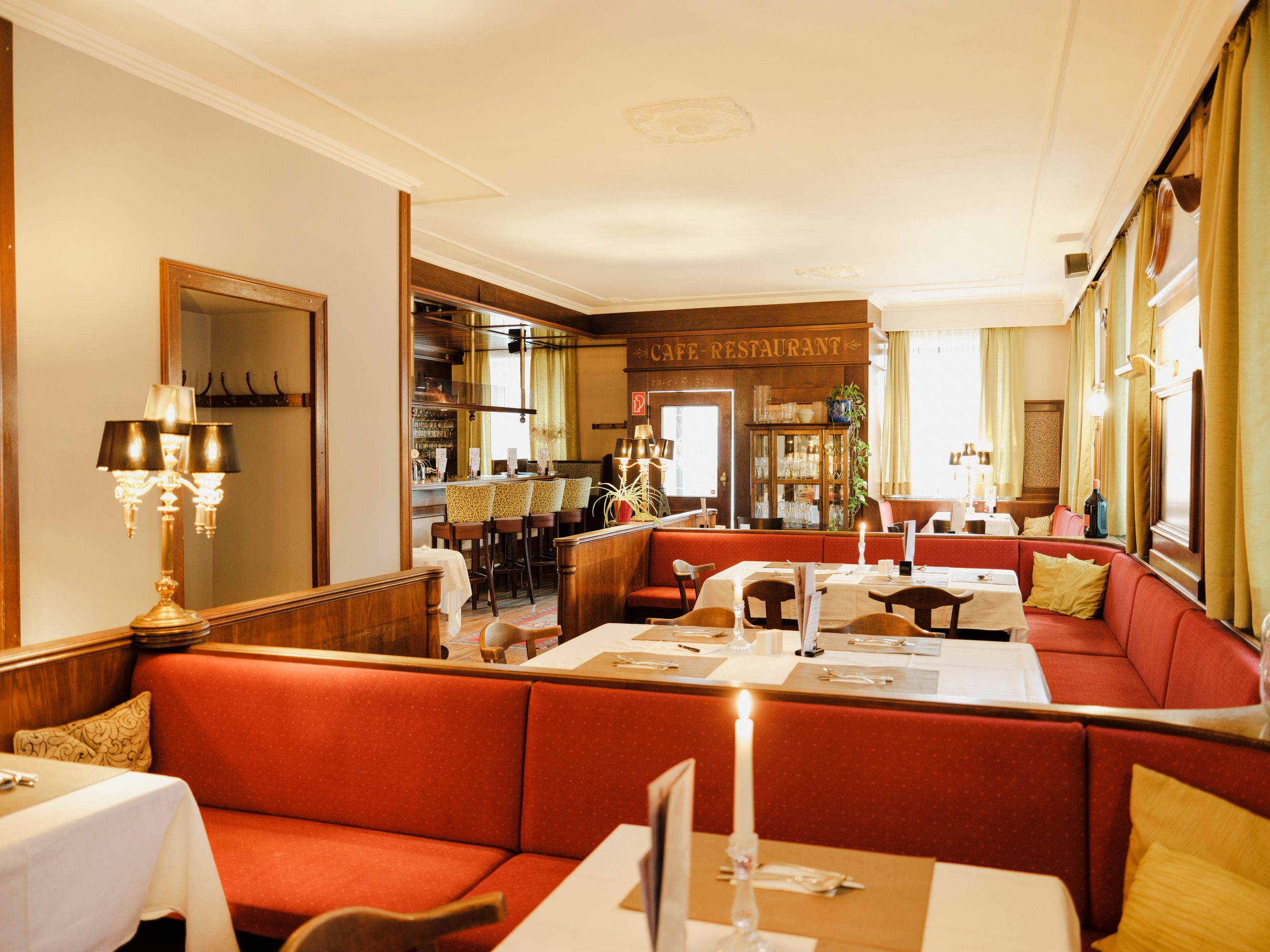 Gemütliches Café-Restaurant mit roten Sitzbänken und Kerzenlicht.