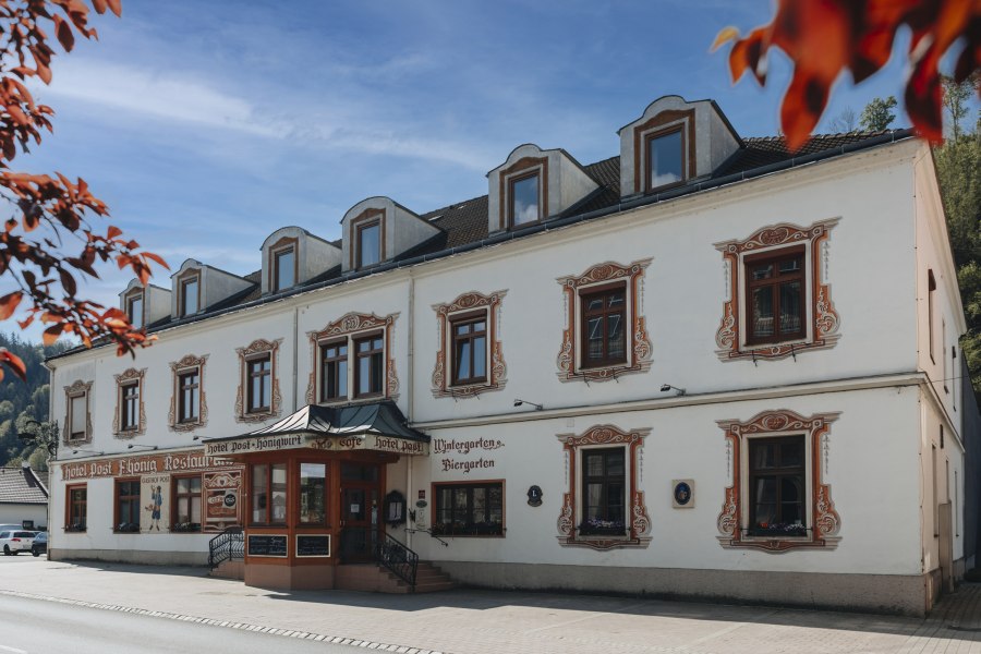 Historisches Gebäude mit dekorativen Fensterrahmen und Schildern für Hotel und Restaurant.