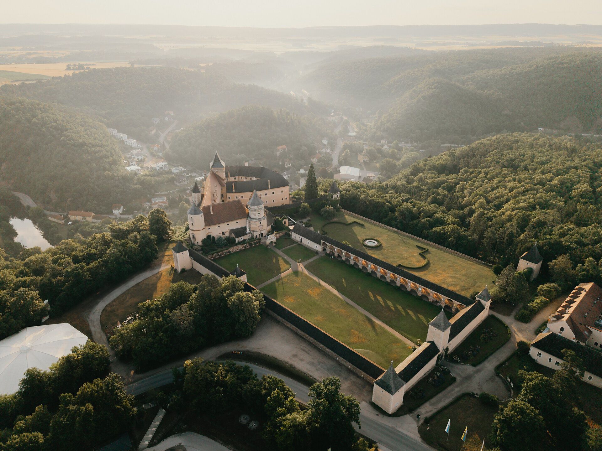 Luftaufnahme eines kleinen Holzstegs am Ufer eines Sees, umgeben von dichtem Wald, im Waldviertel.