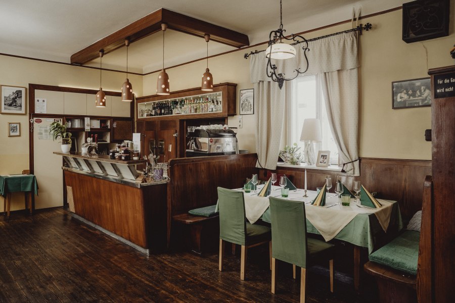 Gem&uuml;tliches Caf&eacute; mit Holzm&ouml;beln, gedecktem Tisch und Barbereich.