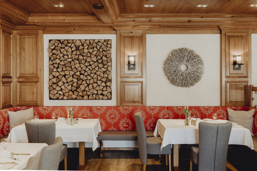Ein stilvoll eingerichteter Restaurantbereich mit Holzw&auml;nden, roten Polstern und dekorativen Wandkunstwerken.