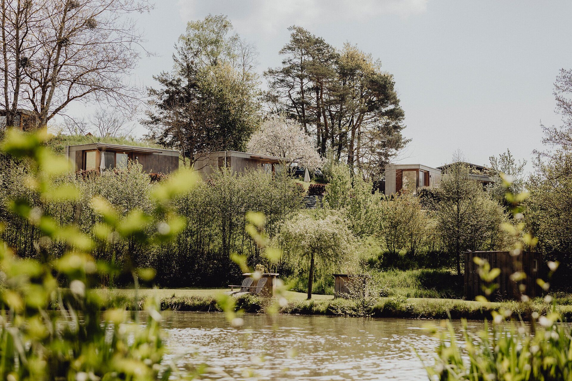 Inmitten einer malerischen Landschaft erheben sich moderne Hütten sanft über dem glitzernden Wasser. Die frische Luft und das sanfte Rauschen der Bäume laden dazu ein, die Seele baumeln zu lassen und die Schönheit der Natur zu genießen.