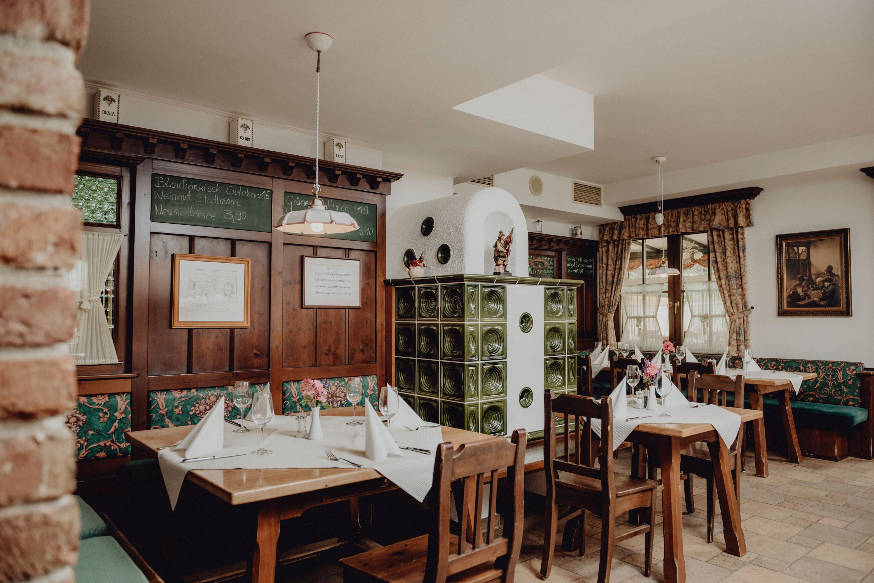 Gemütliches Restaurant mit Holzmöbeln, Kachelofen und dekorierten Tischen.