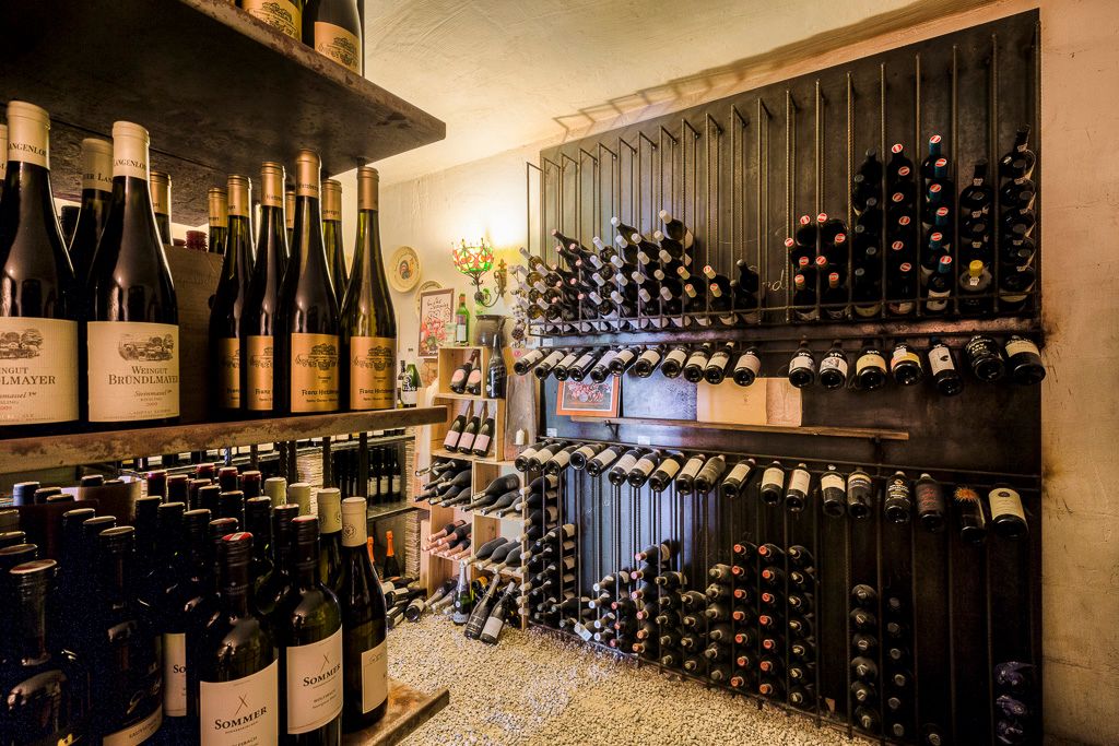 Ein Weinkeller mit Regalen voller Weinflaschen, die ordentlich gestapelt sind.