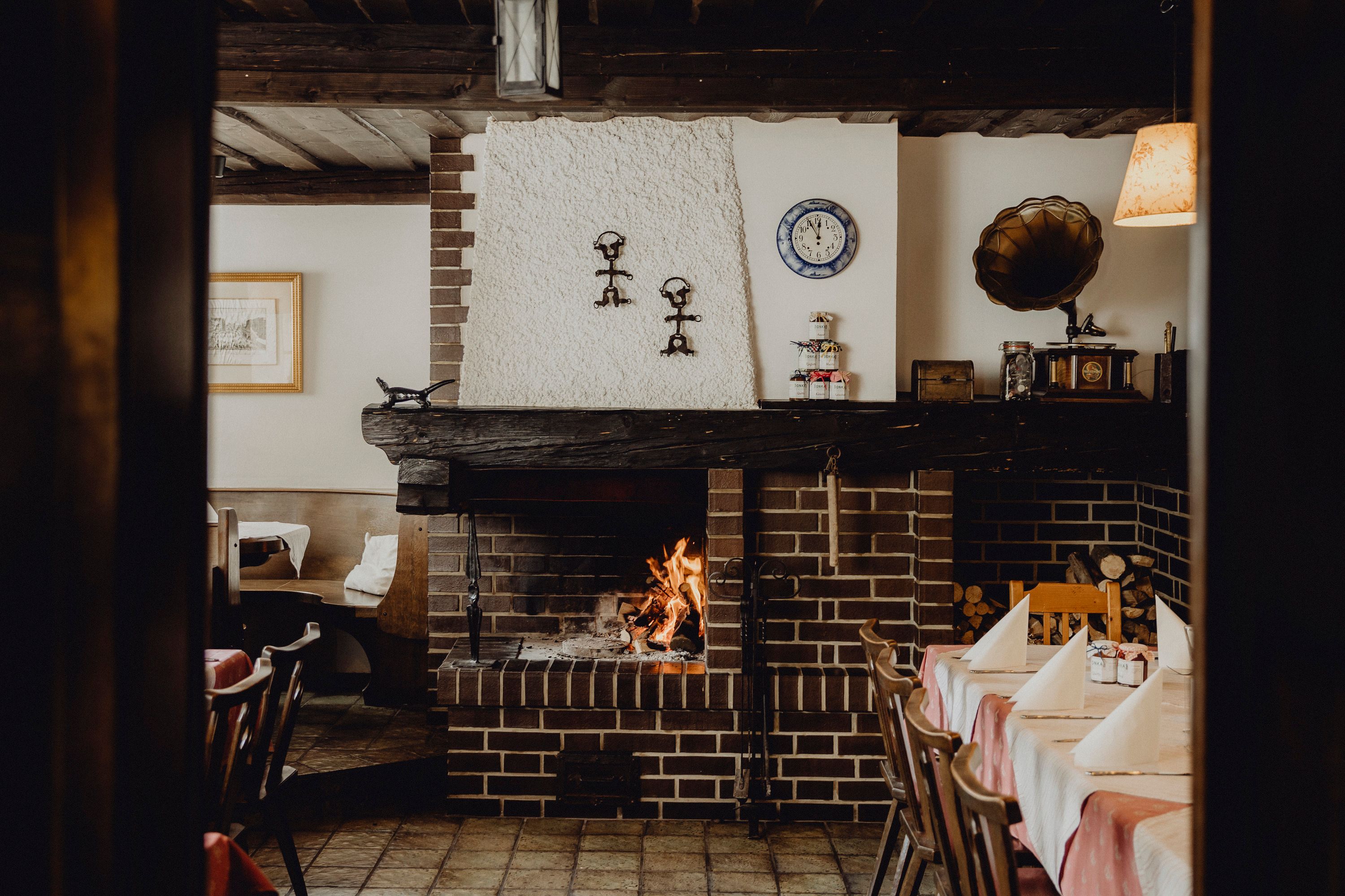 Gemütliches Restaurant mit Kamin, rustikaler Einrichtung und gedecktem Tisch.