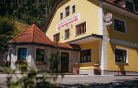 Gelbes Gebäude mit der Aufschrift 'Gasthof zur Roten Säge' und einem Kaiser-Bierschild.