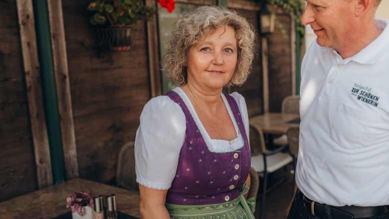 Eine Frau in traditioneller Kleidung steht neben einem Mann in einem weißen Hemd mit Aufschrift.